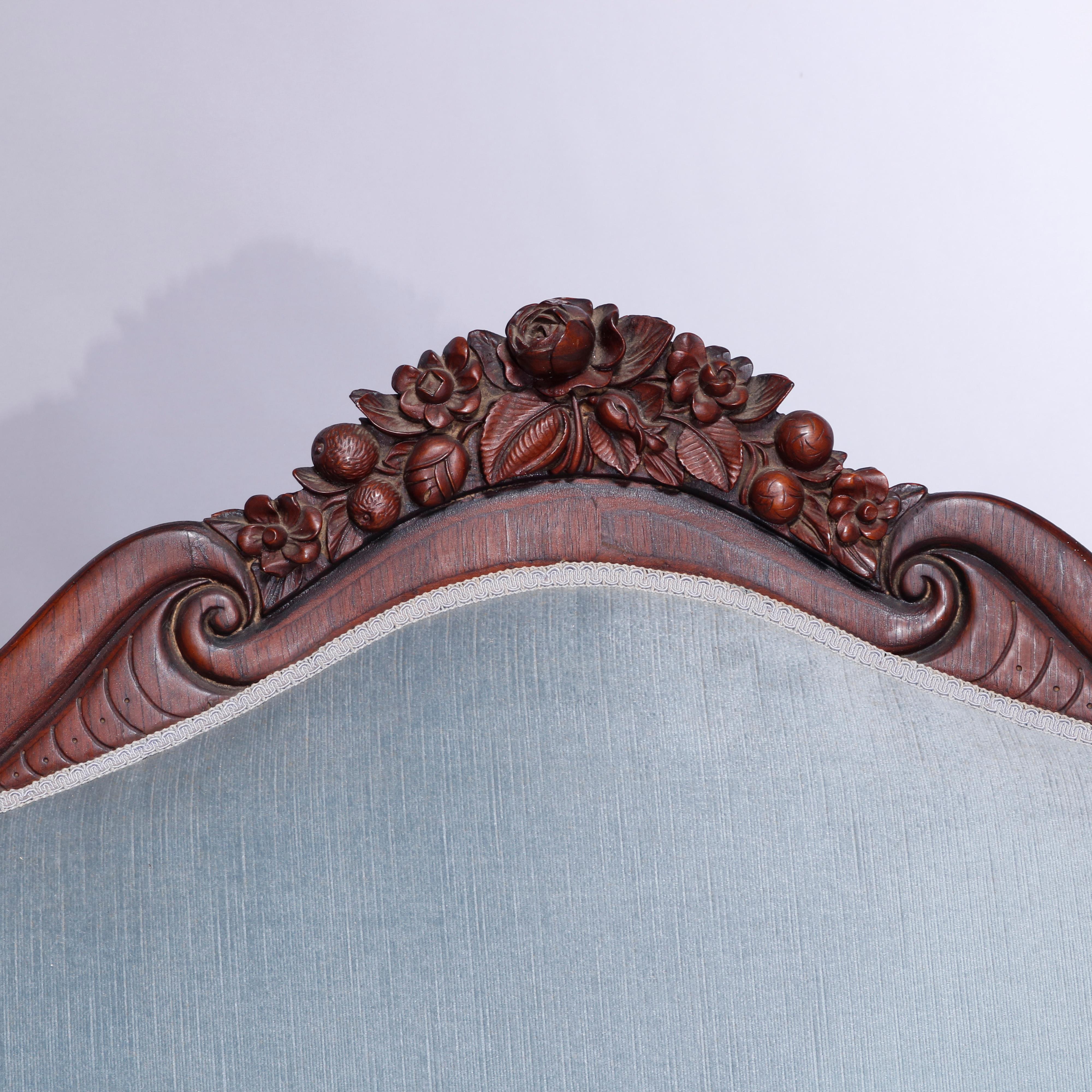 An antique Rococo Revival Belter Rosalie sofa settee offers laminated rosewood construction in serpentine form with shaped back having carved still life crest with fruit, flowers and nuts over upholstered seat and back with flanking scroll form