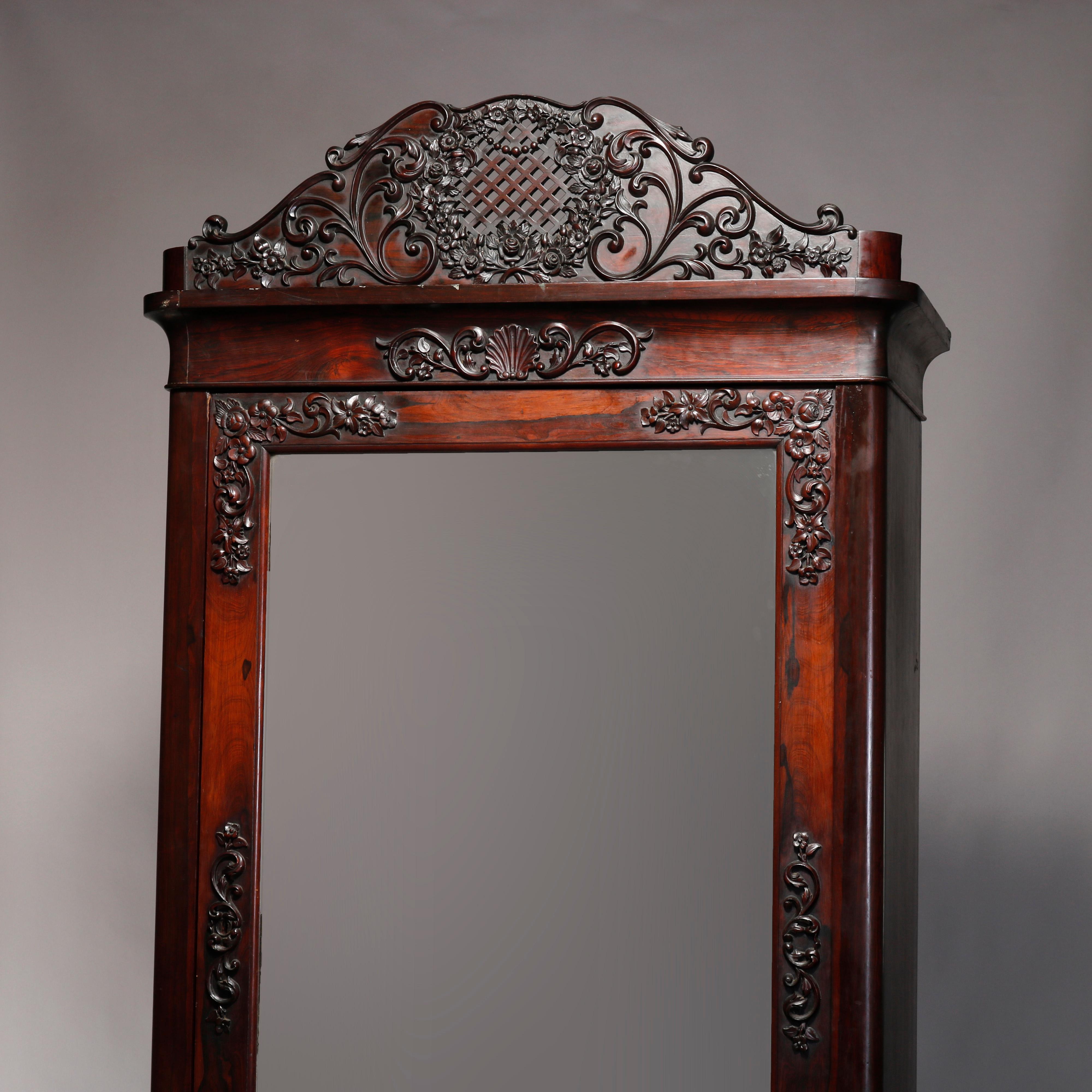 An antique Rococo Revival armoire offers rosewood construction with carved crest having scroll, floral and foliate elements surmounting single mirrored door case and lower drawer, circa 1860

Measures: 93.5