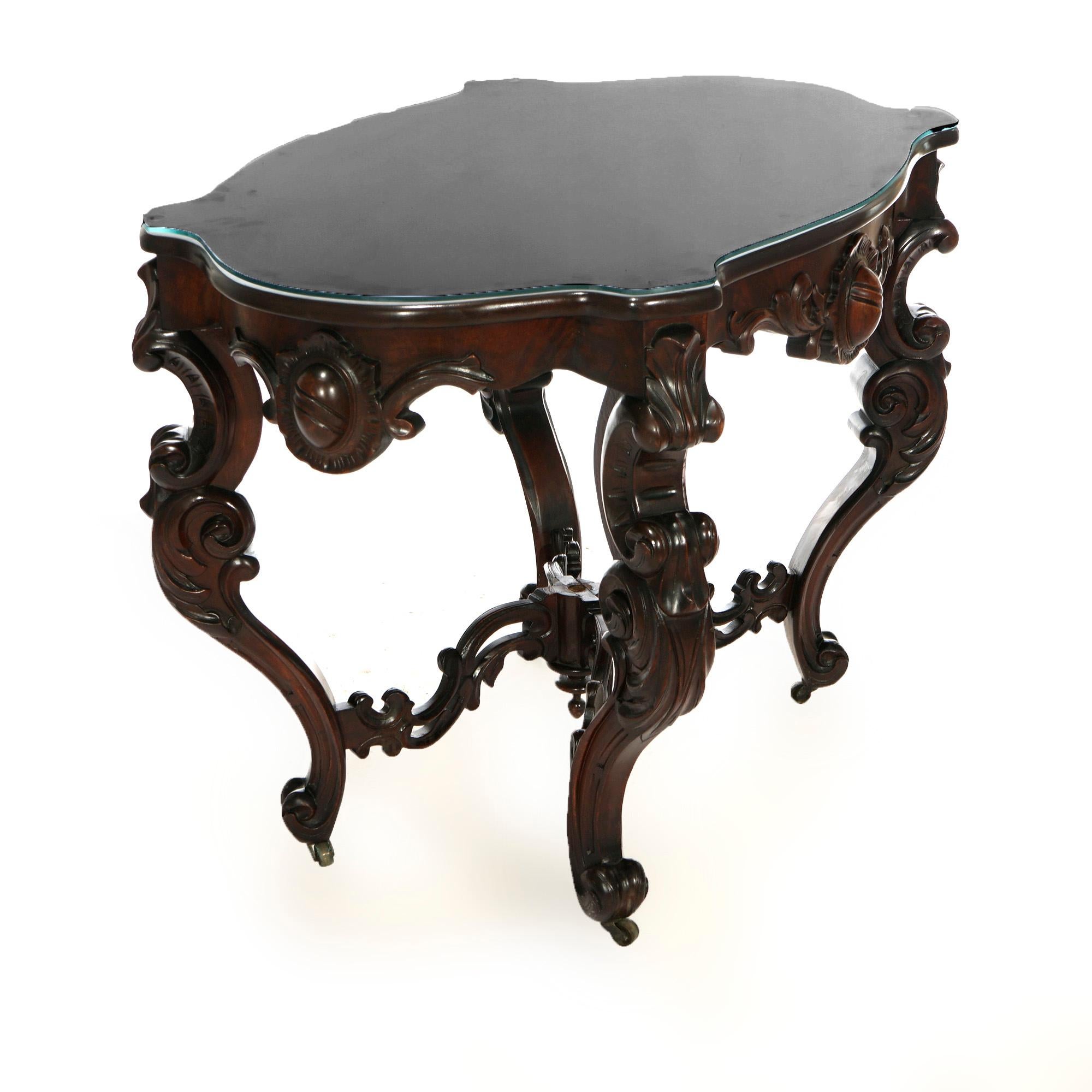 An antique Rococo Revival parlor table offers shaped marble turtle top over walnut base having carved scroll and foliate decoration, raised on scroll form cabriole legs with stretcher having central finial, 19th century

Measures- 30.25'' H x