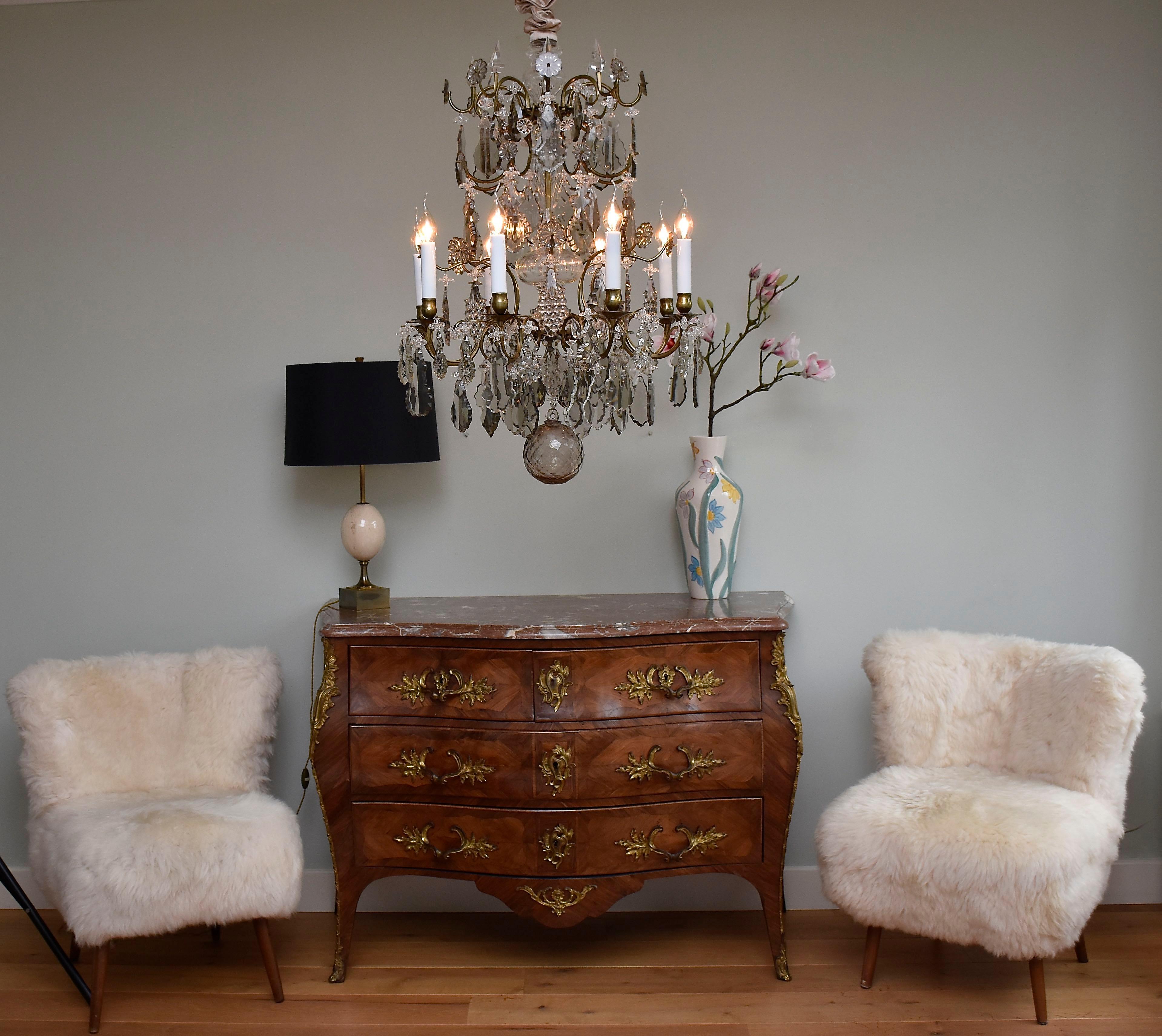 A beautiful Rococo style chandelier with 8 lights.
The chandelier is richly decorated with clear and soft coloured crystal pendeloques and flower rosettes.
The central stem is covered with beautiful decorative vases.
At the bottom of the chandelier