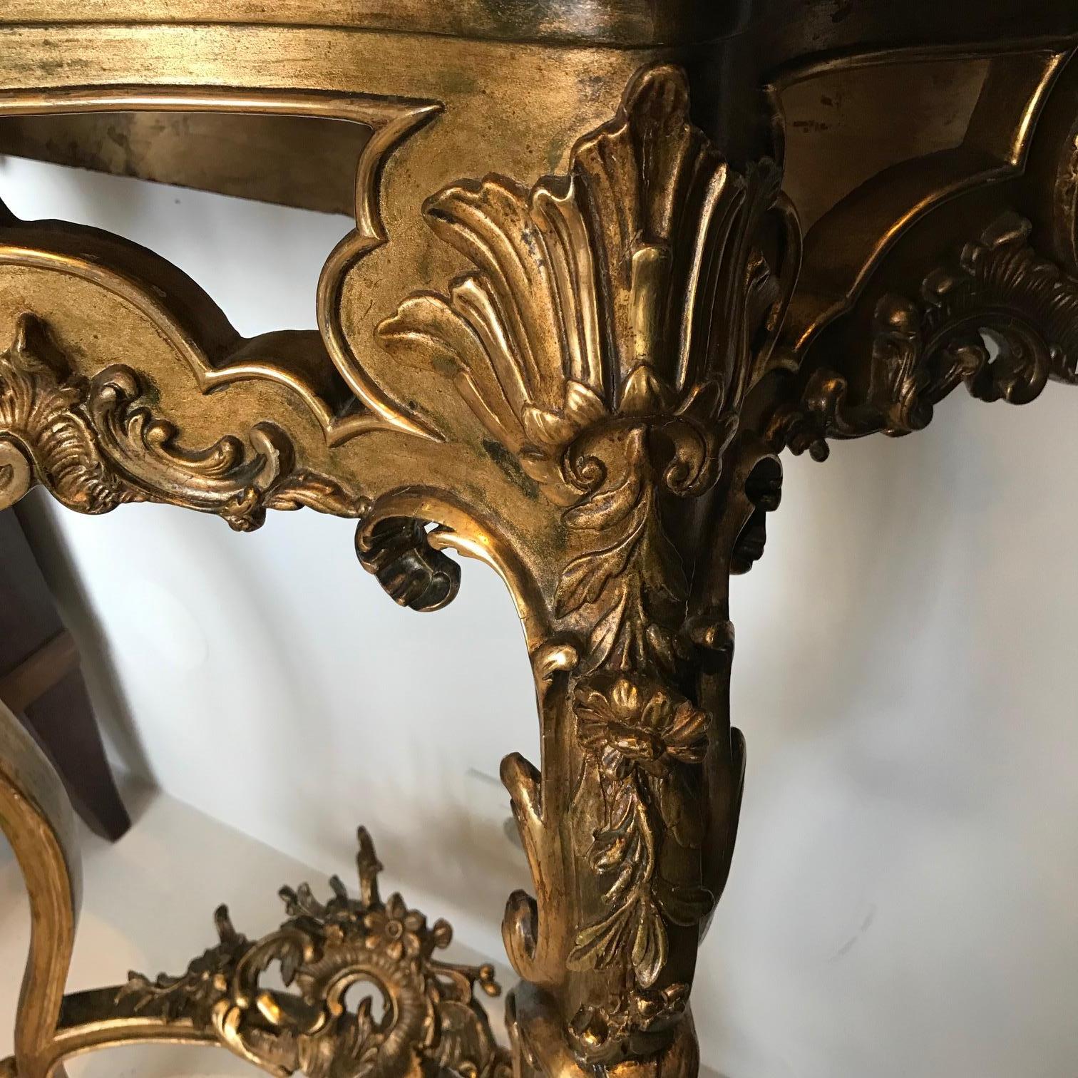 This lovely Rococo Revival console table from the mid-19th century comes from France. It has white Carrara marble serpentine top. The all body is gilded some parts are bolded in high gloss. Along the cabriole legs waving stylized Acanthus leaf. They