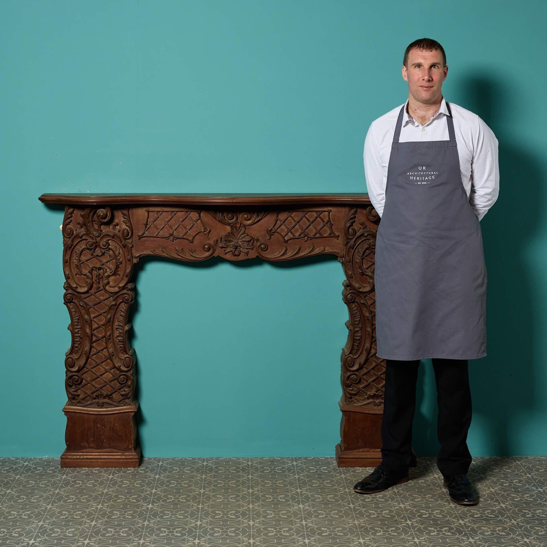 An unusual antique Rococo style carved mahogany fire surround, reclaimed from a house in Evesham. Featuring beautiful curves, scrolls and latticework throughout, this early 20th century antique fireplace is instilled with the opulence of the Rococo