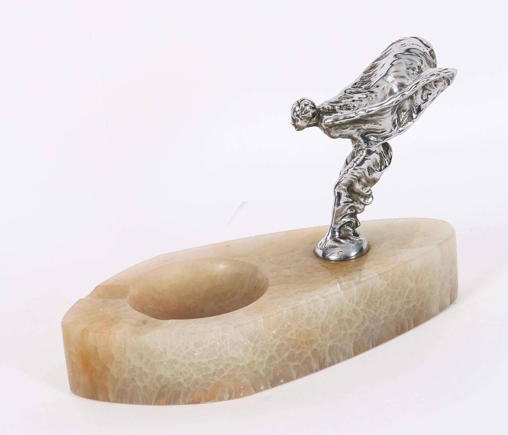 Magnifique mascotte de voiture ancienne Rolls Royce en métal argenté sur un socle en albâtre, The Spirit of Ecstasy et datant de 1929-1939.

La vierge ailée a été conçue par Charles Robinson Sykes (1875-1950). Elle porte la mention 