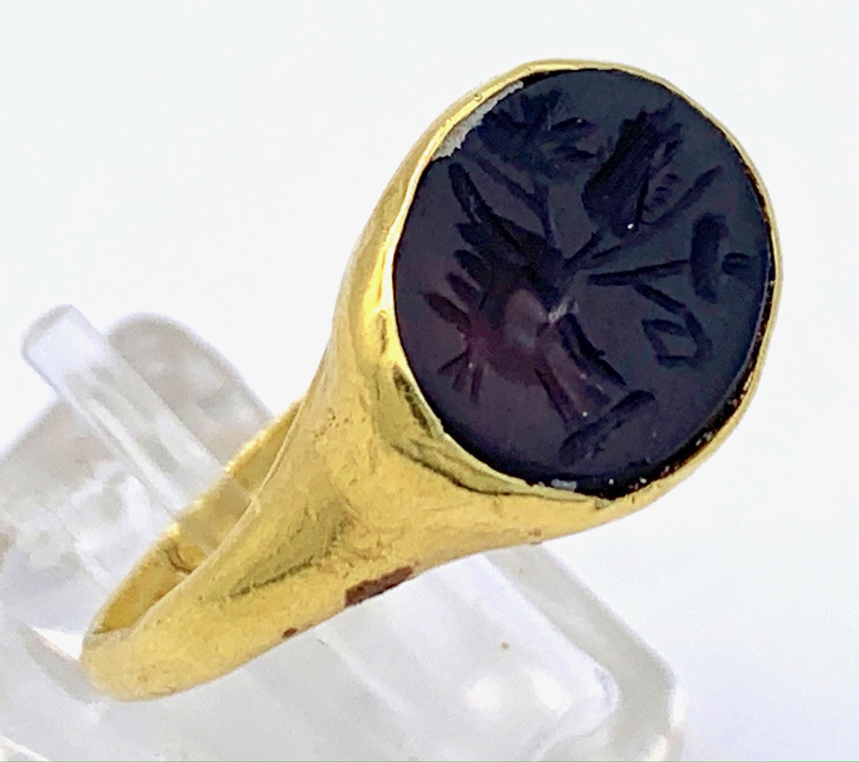 This 18 karat gold ring is set with a deep brown agate intaglio. The roman intaglio dates from the second / third century AC and depicts a hand holding a oar, a poppy and one other flower. The intaglio was supposed to bring fortune, prosperity,