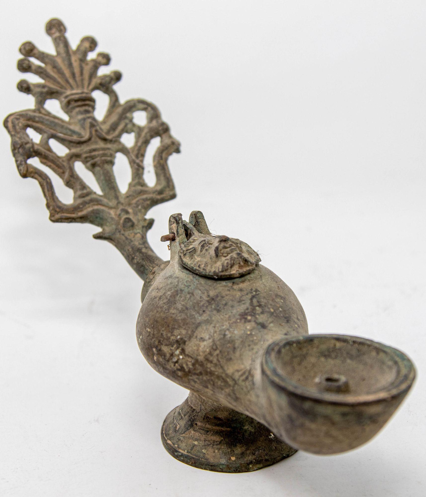 Lampe à huile antique en bronze de style romain byzantin, avec une poignée ajourée, percée d'une fronde de palmier et d'un col de cygne, un corps en forme de poire et une bouche de mèche circulaire, centrée par un couvercle à charnière en forme de