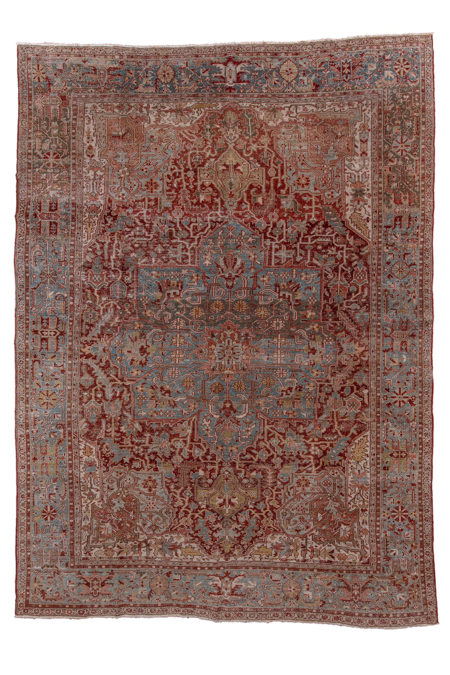 The well-filled, irregular cartouche-shaped red field of this rustic roomsize carpet presents a teal medallion with escutcheon anchor pendants. Barbed leaves and broken vinery are particularly salient field decorations.  Ecru corners.  Light blue