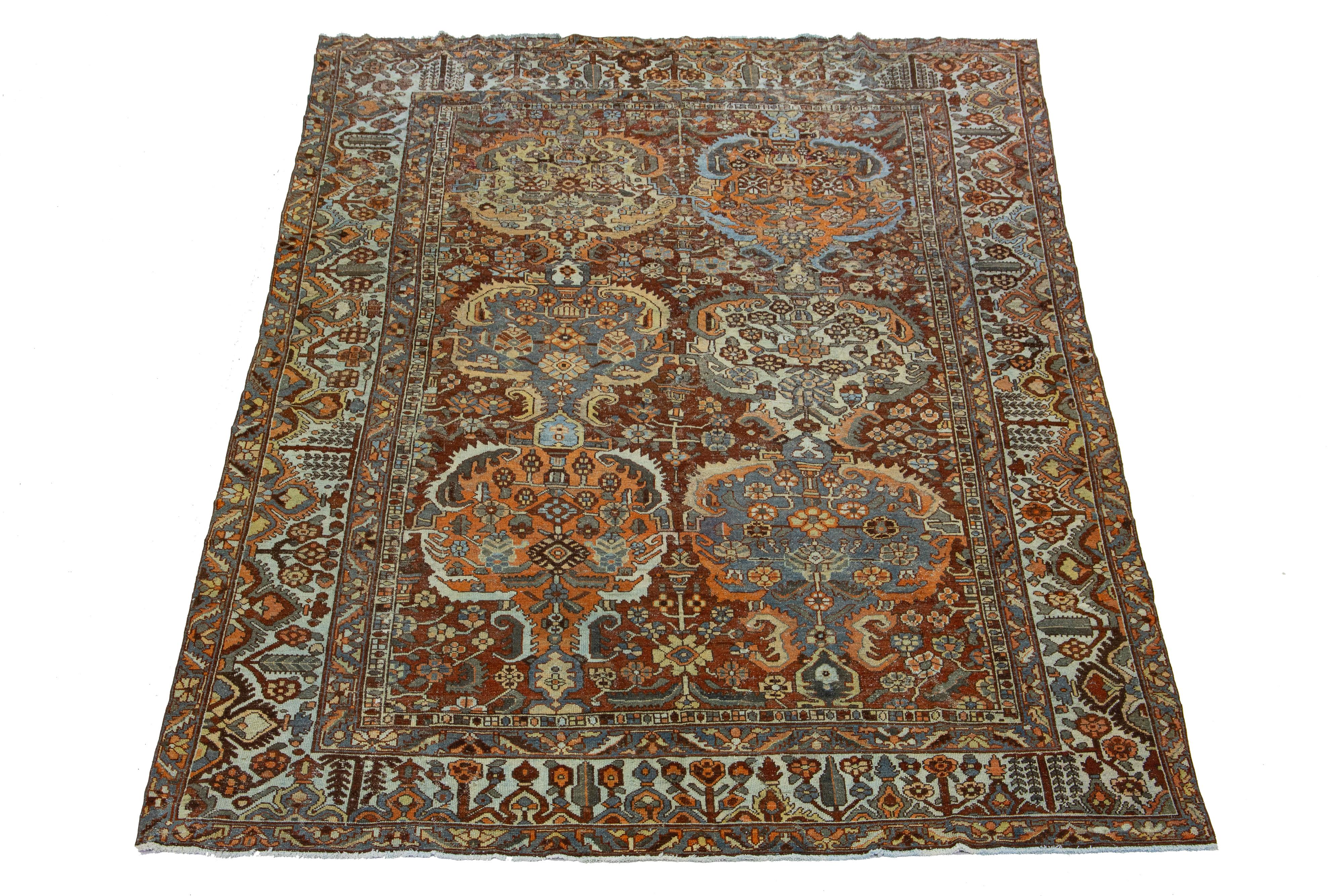 Beautiful Antique Bakhtiari hand-knotted wool rug with a red-rust color field. This Persian piece has a classic geometric floral design in blue, orange, and peach colors.

This rug measures 9'8