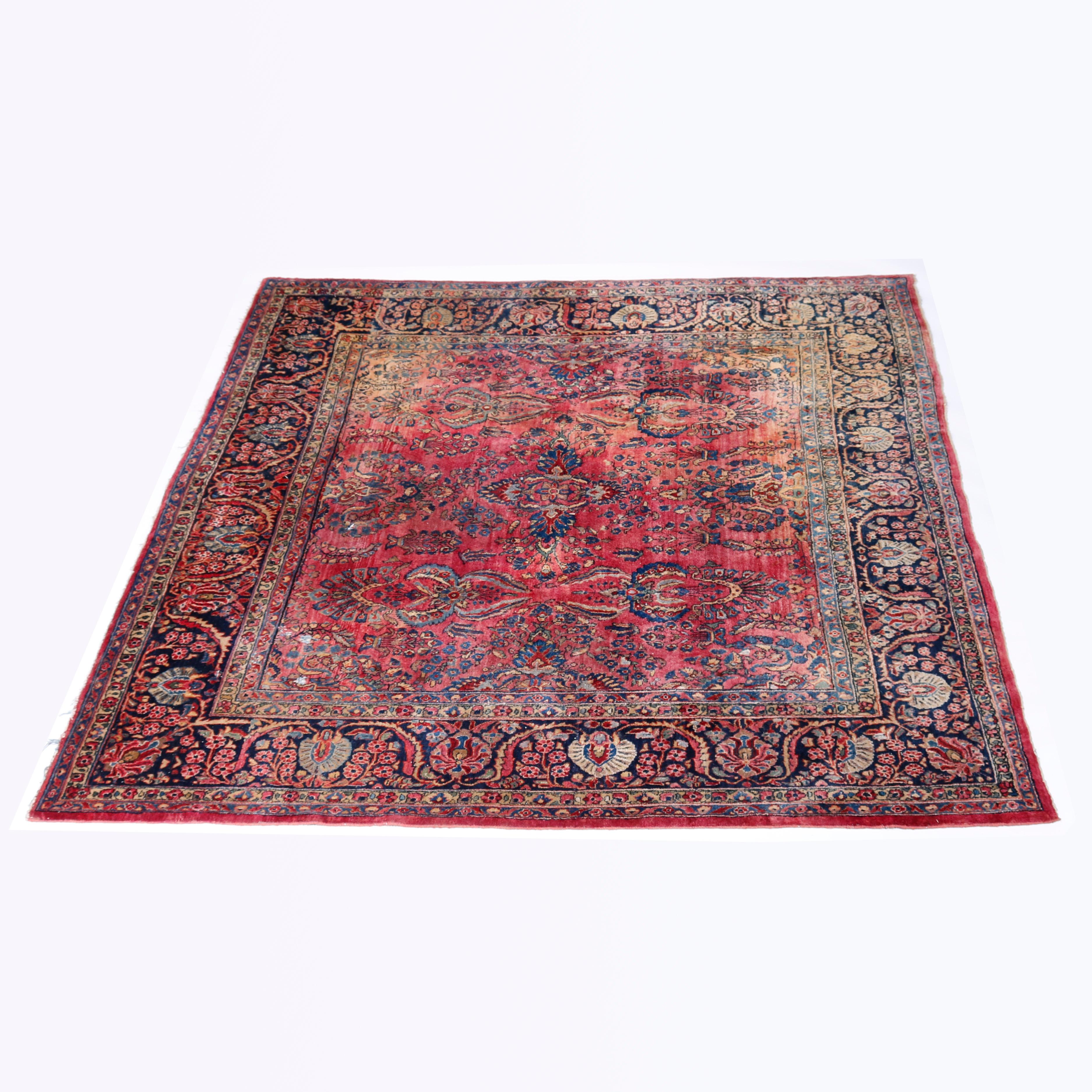 An antique room size Persian Sarouk oriental carpet offers wool construction with central medallion and allover floral and foliate design on red ground, c1930

Measures - 106.5''H x 86''W x .5''D.