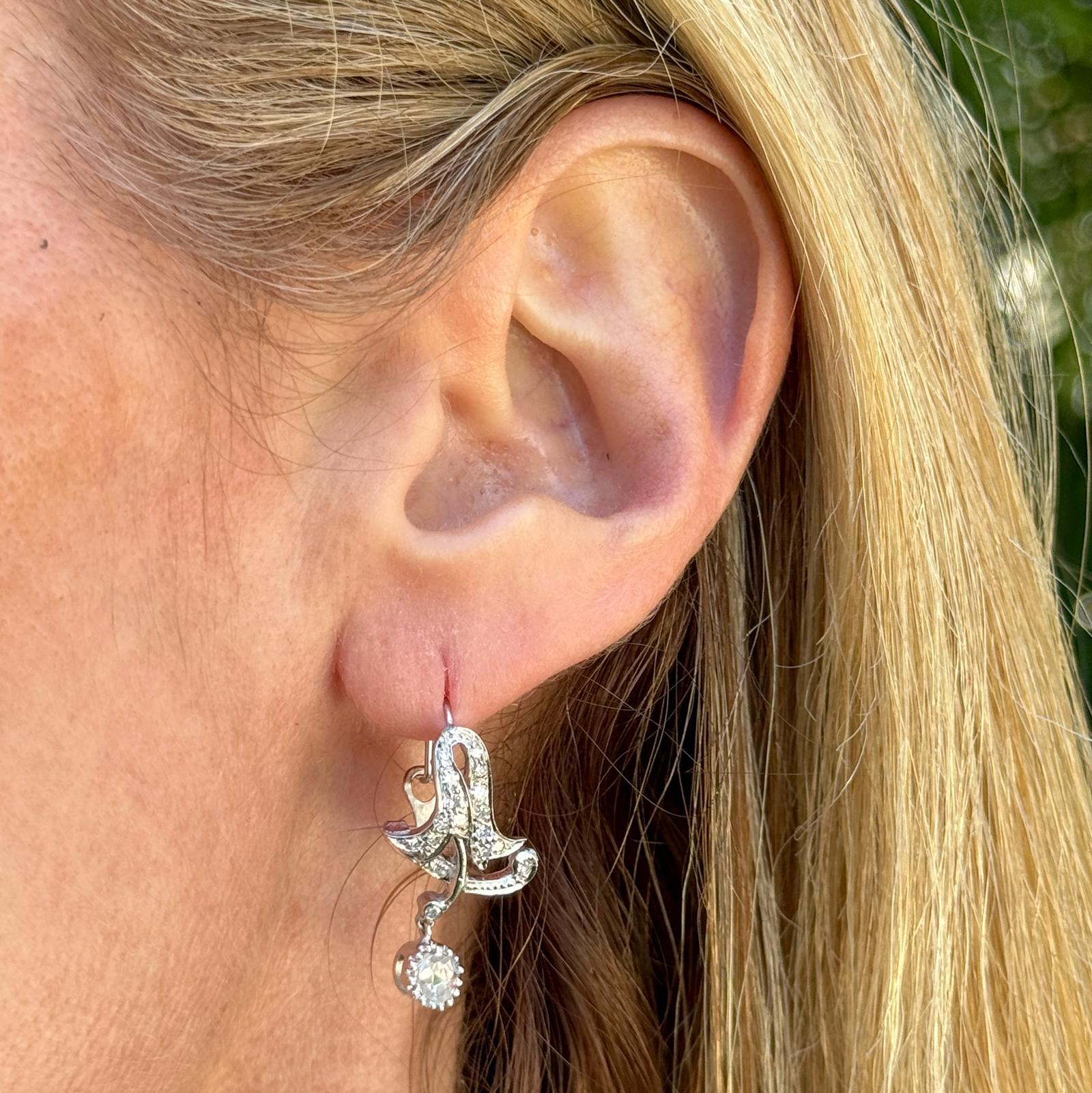 These antique rose cut diamond drop earrings offer a captivating blend of vintage charm and contemporary elegance. Crafted with meticulous attention to detail, they feature luminous 18 karat white gold settings that gracefully dangle 1.10 inches