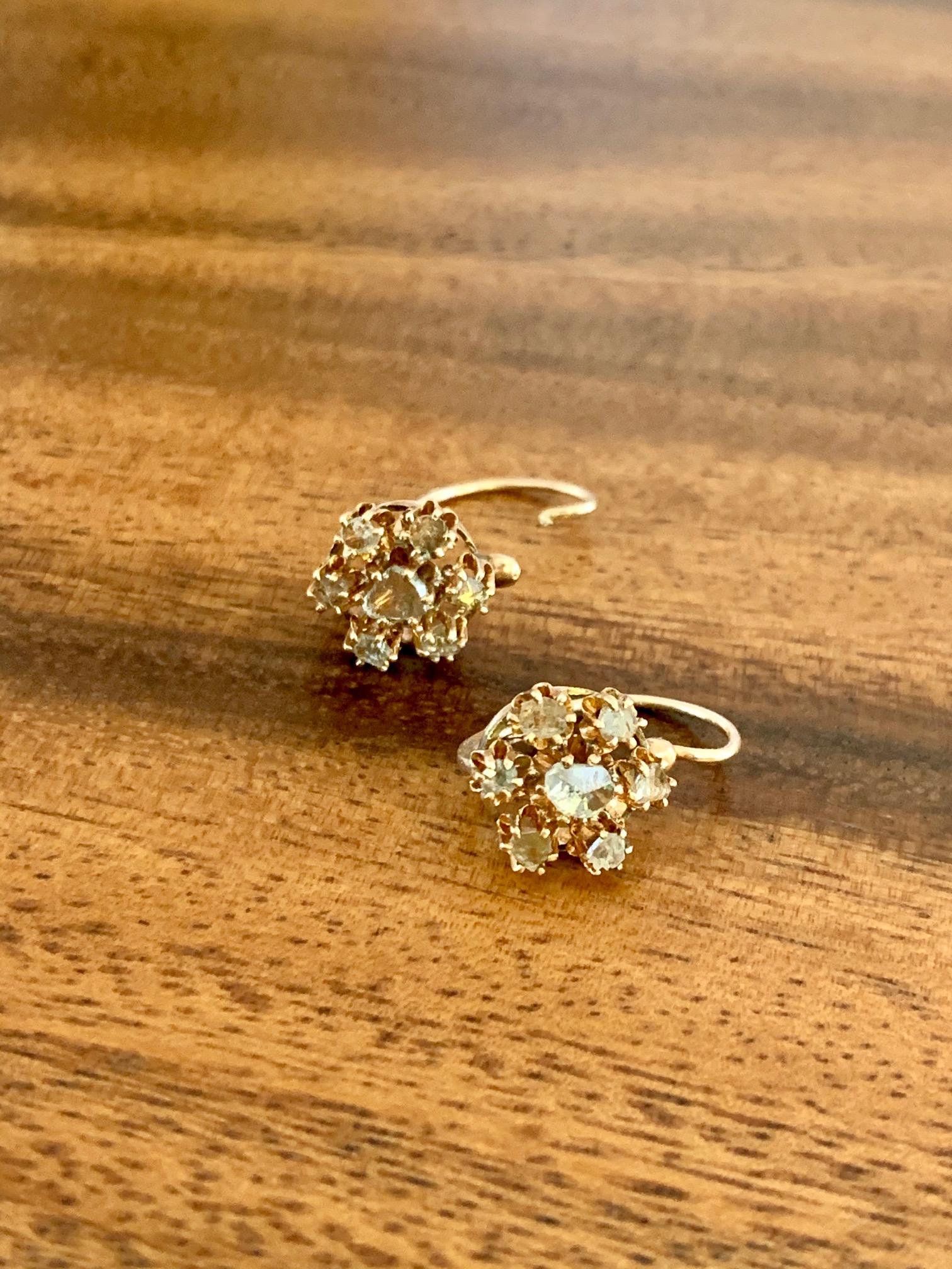 These 9 karat yellow Gold antique earrings feature seven rose cut Diamonds on each earring.  The center stone is slightly larger than the six stones surrounding it.  They feature a front closure.

Weight: 2.4 grams
Cluster size: 3/4