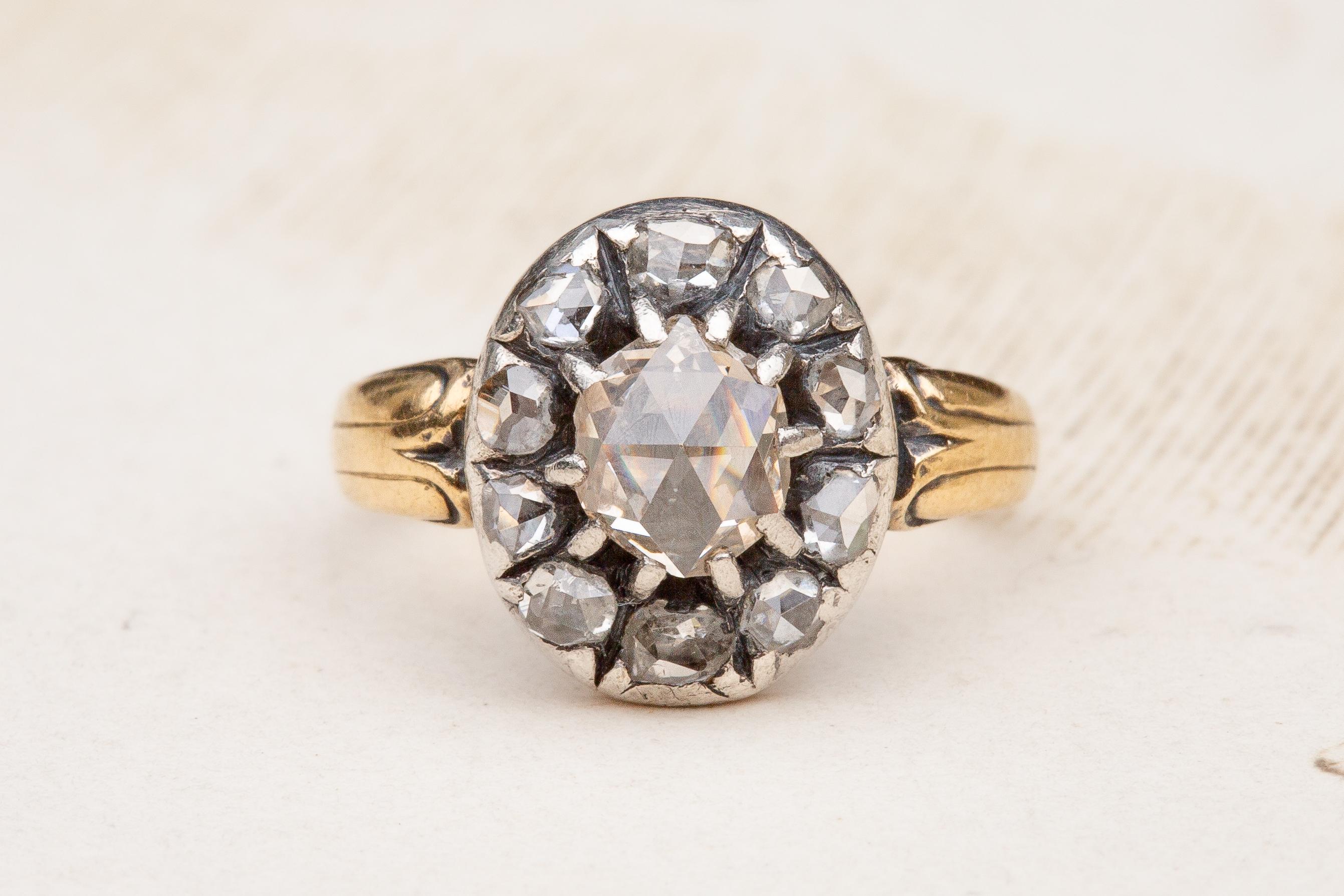 A superb antique early 19th century rose cut diamond cluster ring. 

The silver-topped gold bezel exhibits a gorgeous central domed rose cut diamond of fantastic clarity and a subtle pinkish champagne colour. It is held in position with silver