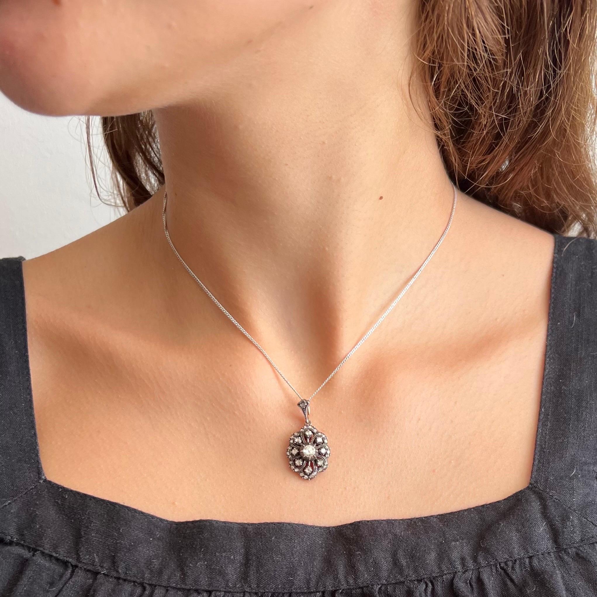 An antique floral rose cut diamond pendant, truly a treasure to behold. This early 20th Century oval-shaped pendant is created with many bright rose cut diamonds set in a silver and gold frame. The diamonds are set in a silver raised dome shaped