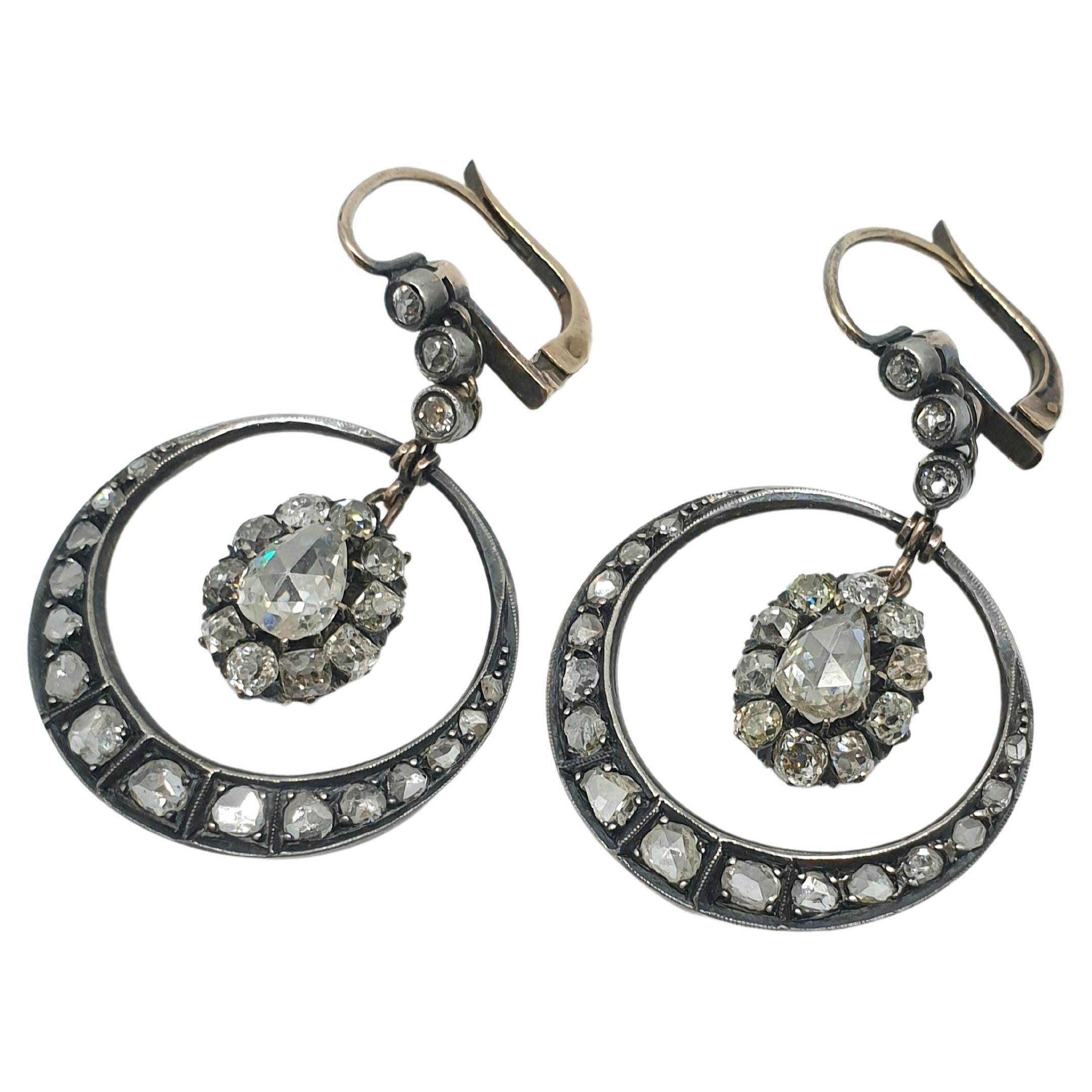 Pendientes grandes antiguos de diamantes talla rosa en diseño de media luna con colgante colgante de forma oval centrado con un diamante talla rosa en forma de pera flanqueado por varios diamantes talla mina antiguos de color blanco excelente brillo