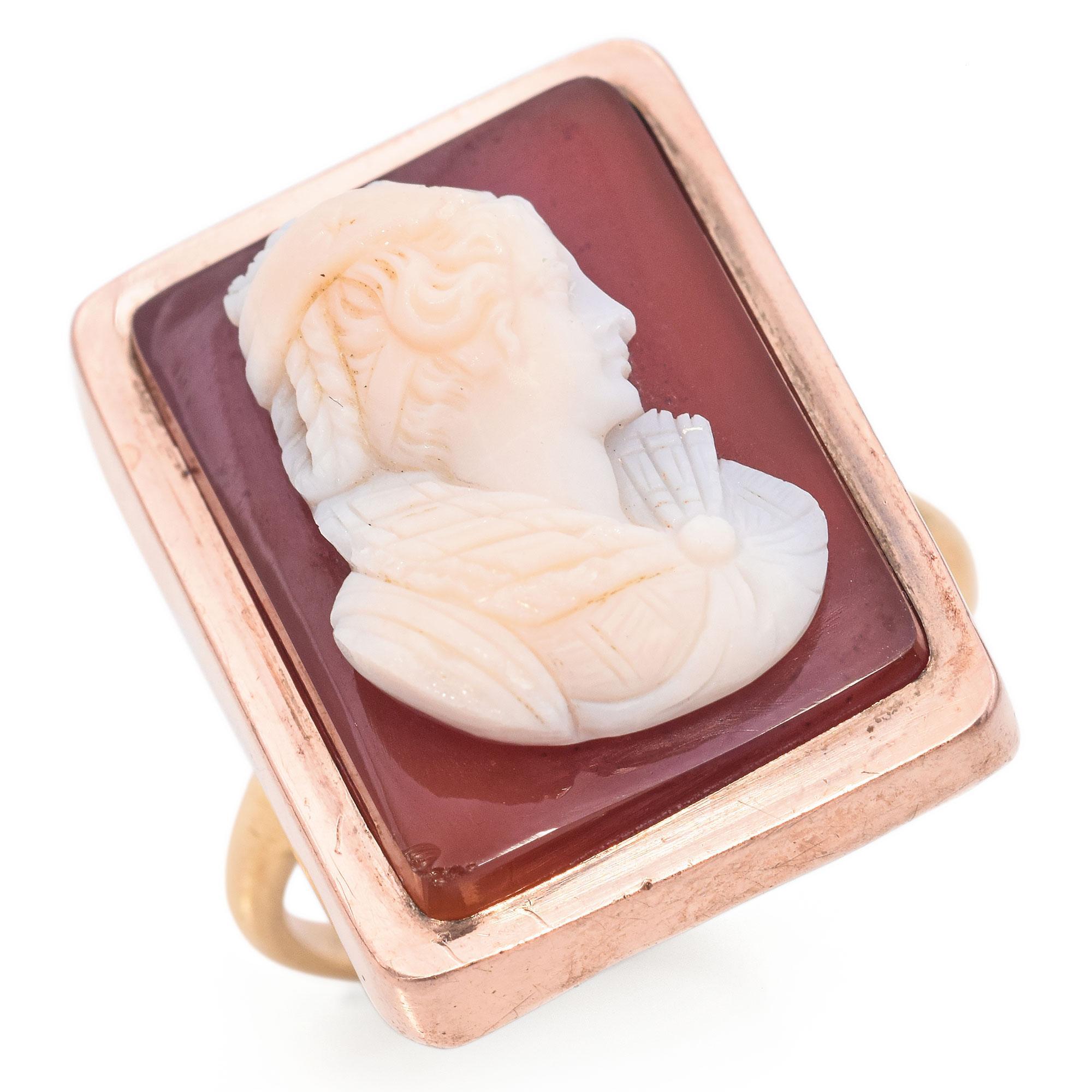 A distinctive ring featuring a rectangular cameo with an intricate noble lady profile carving set against a red hardstone.
The cameo is framed in rose gold, highlighting the detailed craftsmanship of the design.
Crafted in the early 20th century in