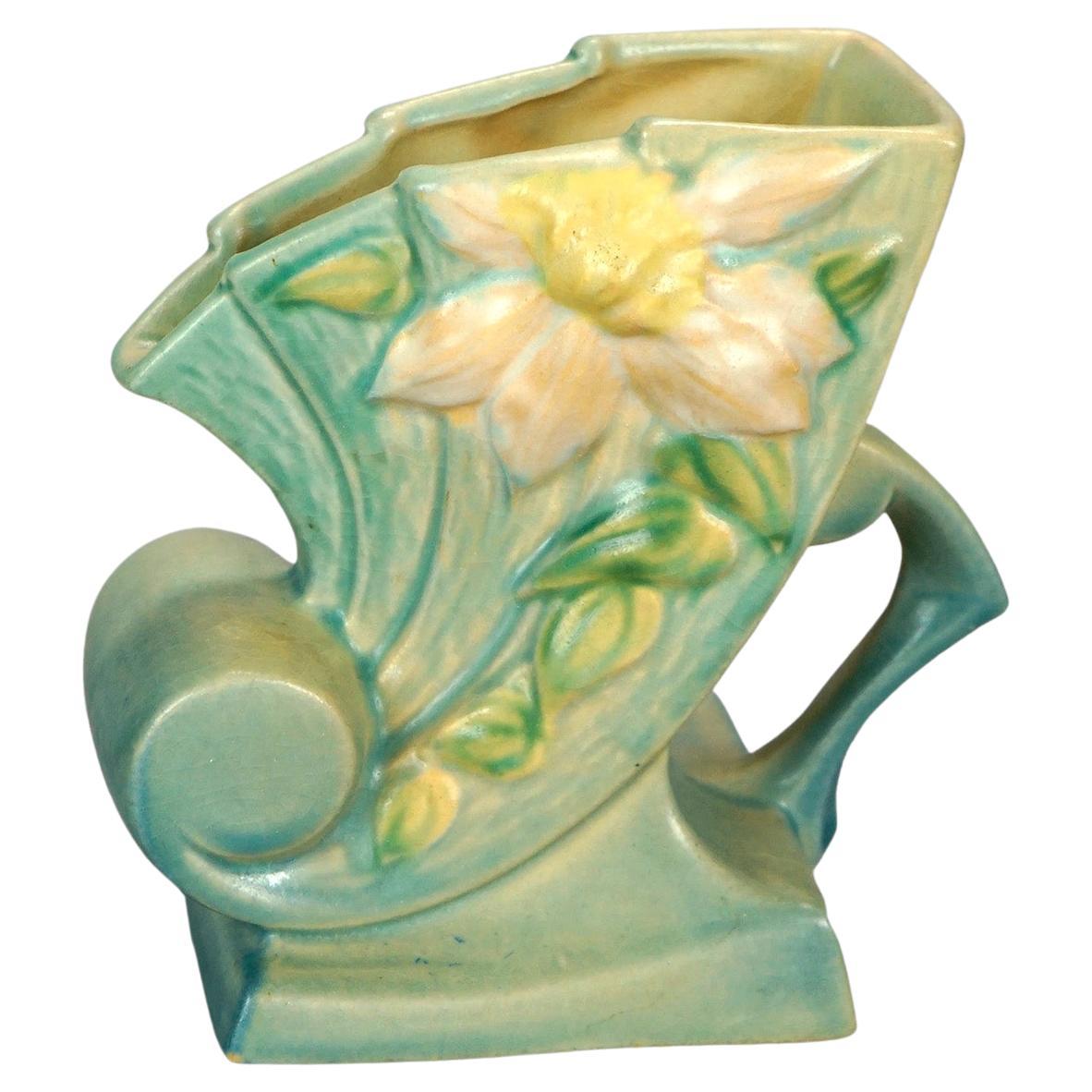 An antique vase by Roseville in the Clematis pattern offers art pottery construction with cornucopia form vessel having handle and foot, maker signed on base as photographed, c1930

Measures- 6.5''H x 6.25''W x 4''D.

Catalogue Note: Ask about