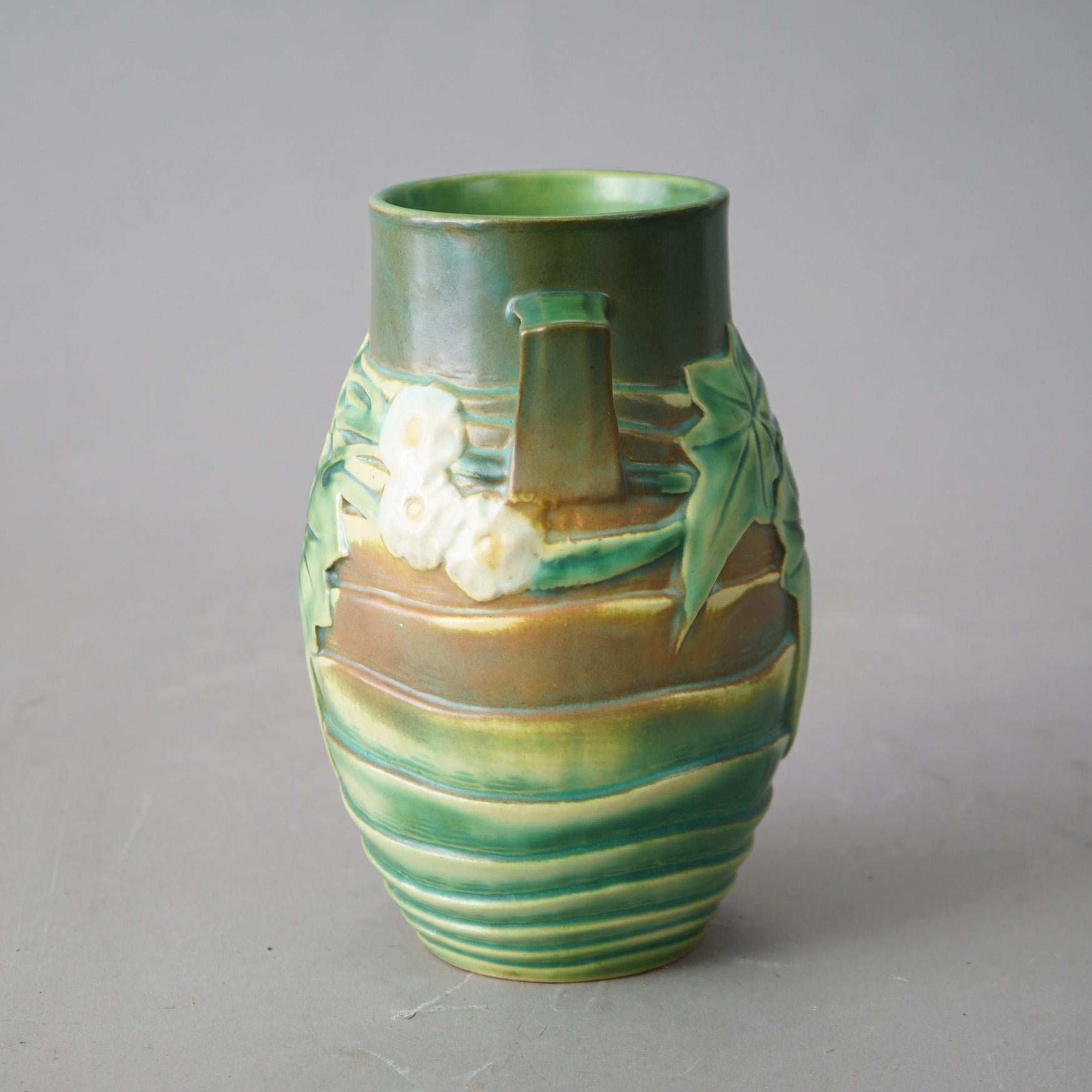 An antique Arts and Crafts vase by Roseville offers art pottery construction in green Luffa pattern with double handles and flowers with leaves, c1930

Measures - 8.25
