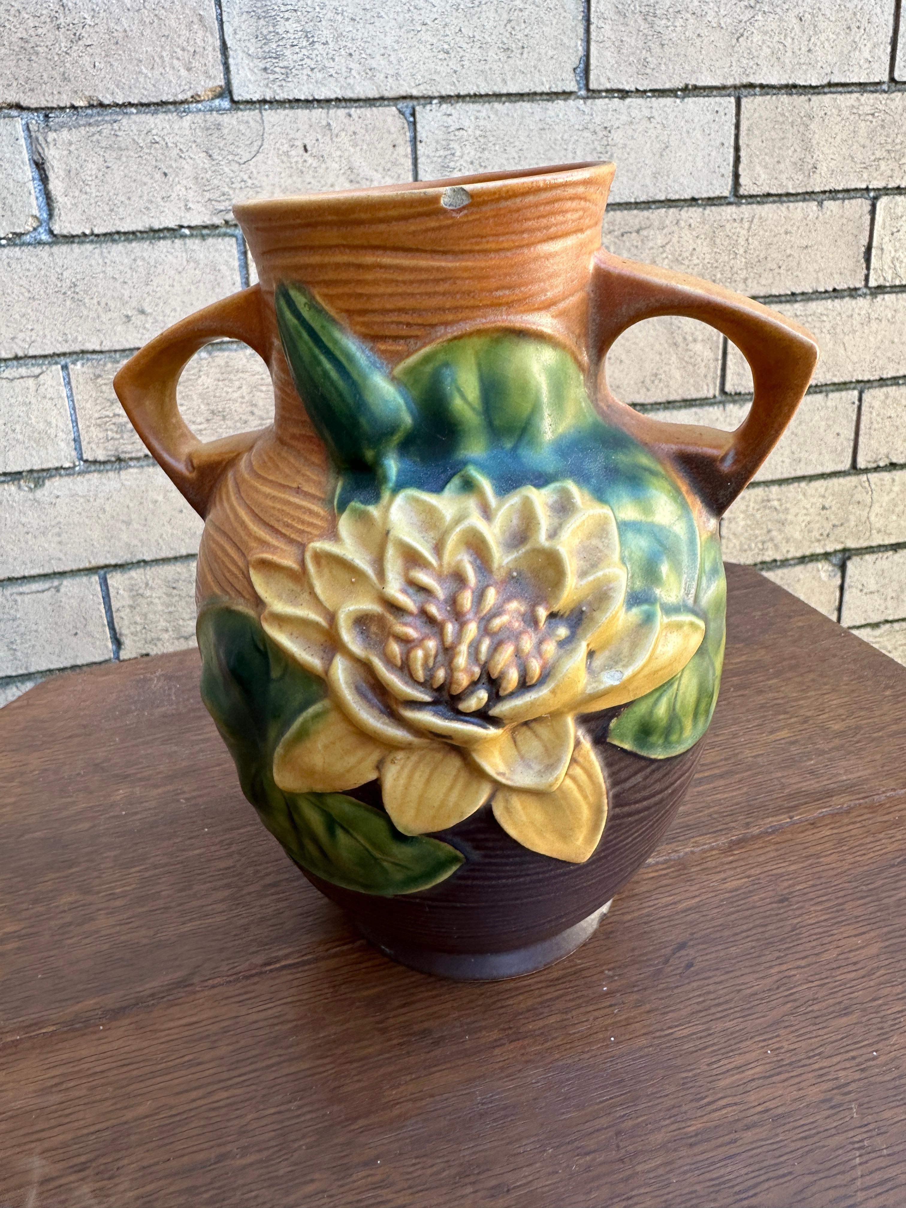Se trata de un precioso jarrón antiguo de la Roseville Vase Company fabricado hacia 1930.  Tiene un diseño de cojín de lirio.  Hay una pequeña muesca en el borde (ver fotos).