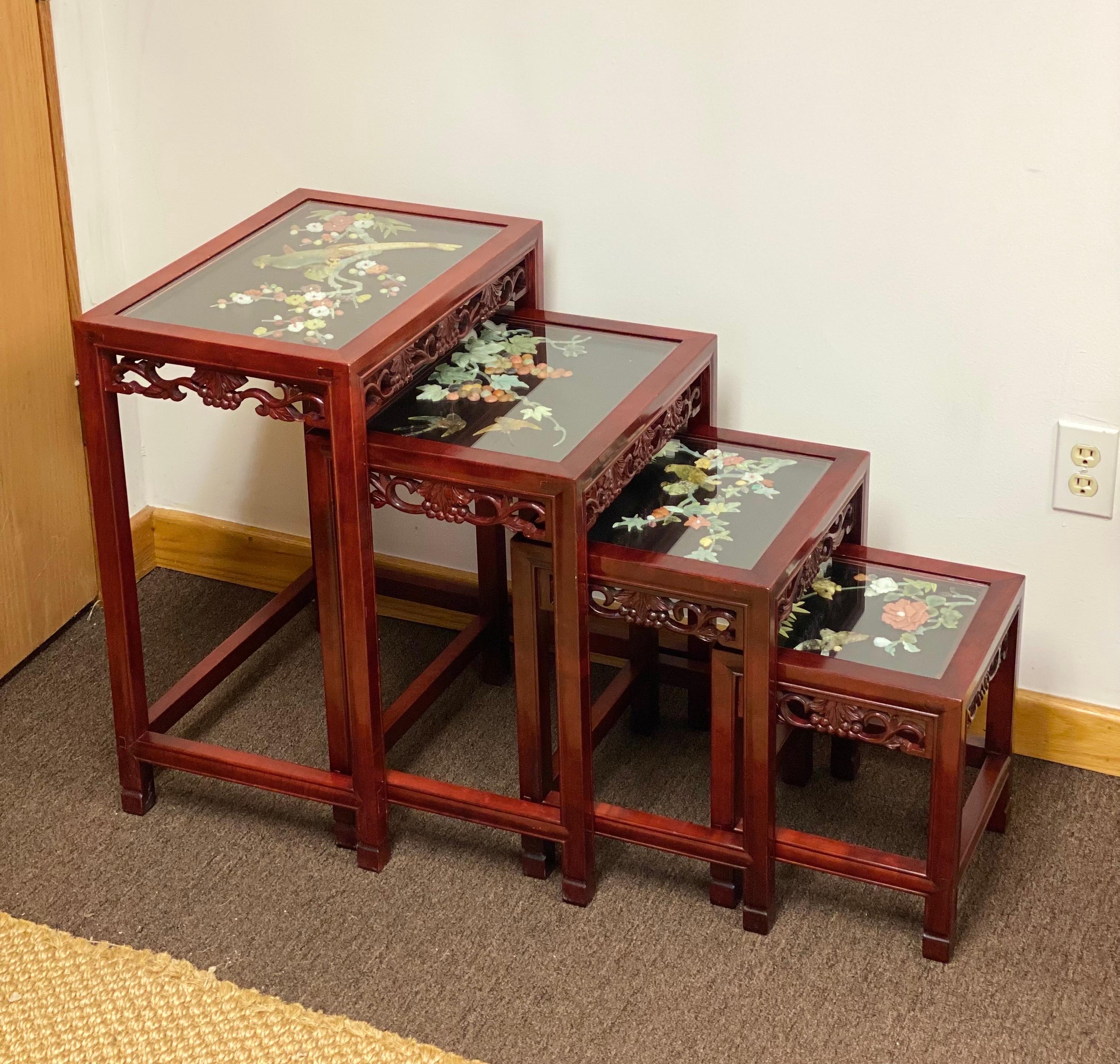 We are very pleased to offer a rare, stunning set of Chinoiserie nesting tables, circa the 1920s. This set of four nesting side tables is the perfect accompaniment to any space. Constructed from beautiful rosewood, they showcase magnificent Jade