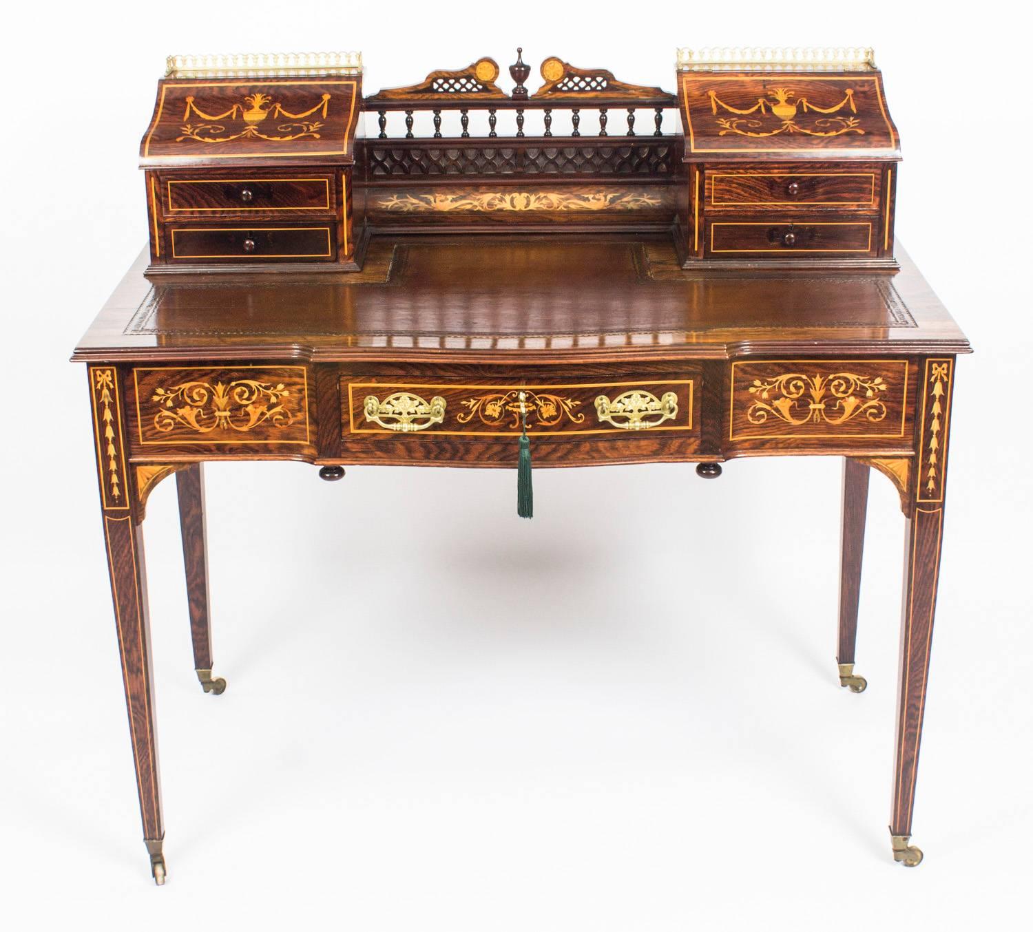 This is a beautiful antique Edwardian rosewood and marquetry Carlton House desk in the manner of the renowned retailer and manufacturer Edwards & Roberts, circa 1900 in date.

The desk is inlaid with a fabulous satinwood marquetry of ribbons,