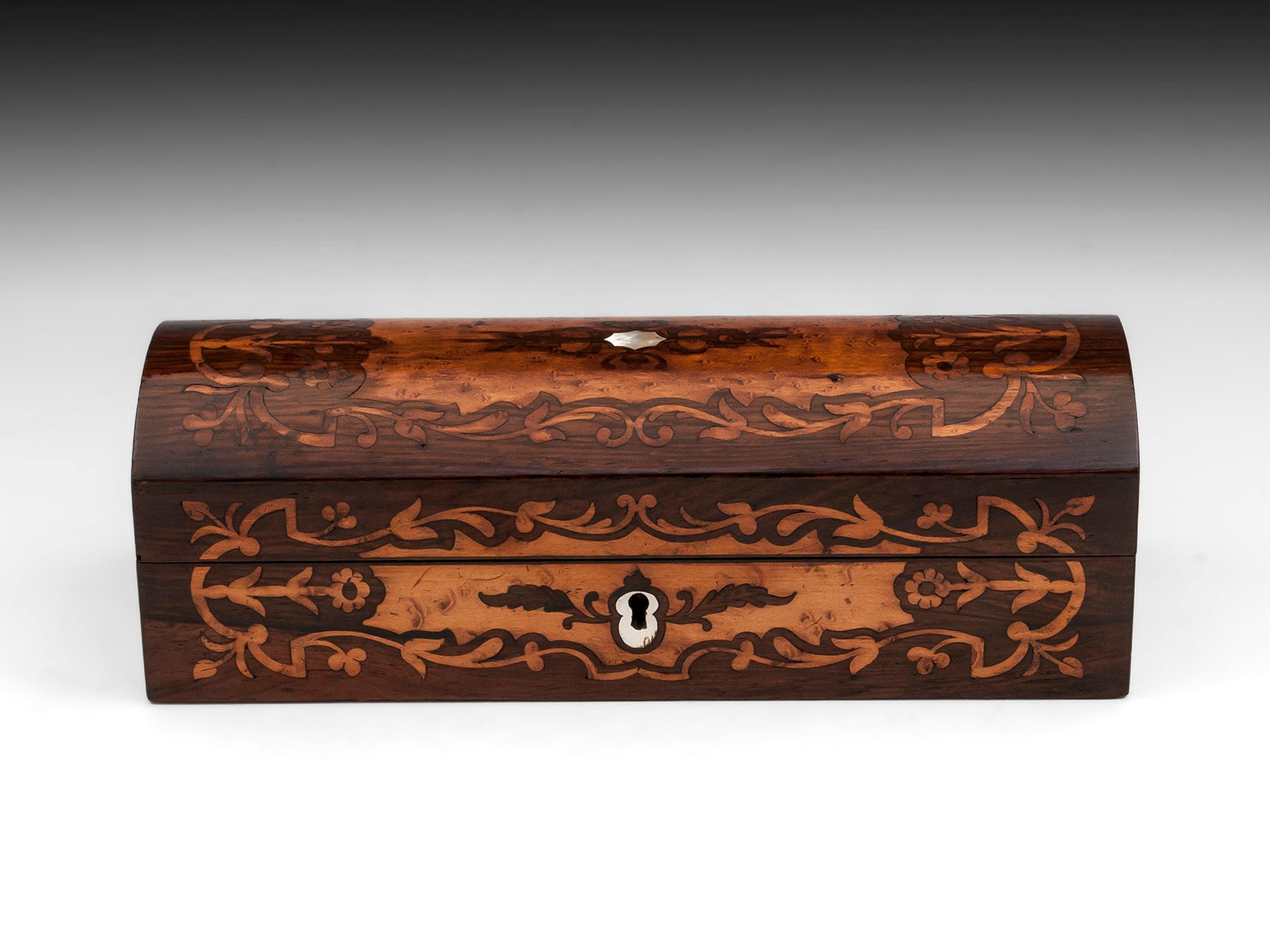 Dome shaped Rosewood Jewelry Box with beautiful bird's-eye maple floral inlays to the front and top. With mother of pearl escutcheon and initial plate. 

The interior has its original lined in patterned paper while the underside of the lid is
