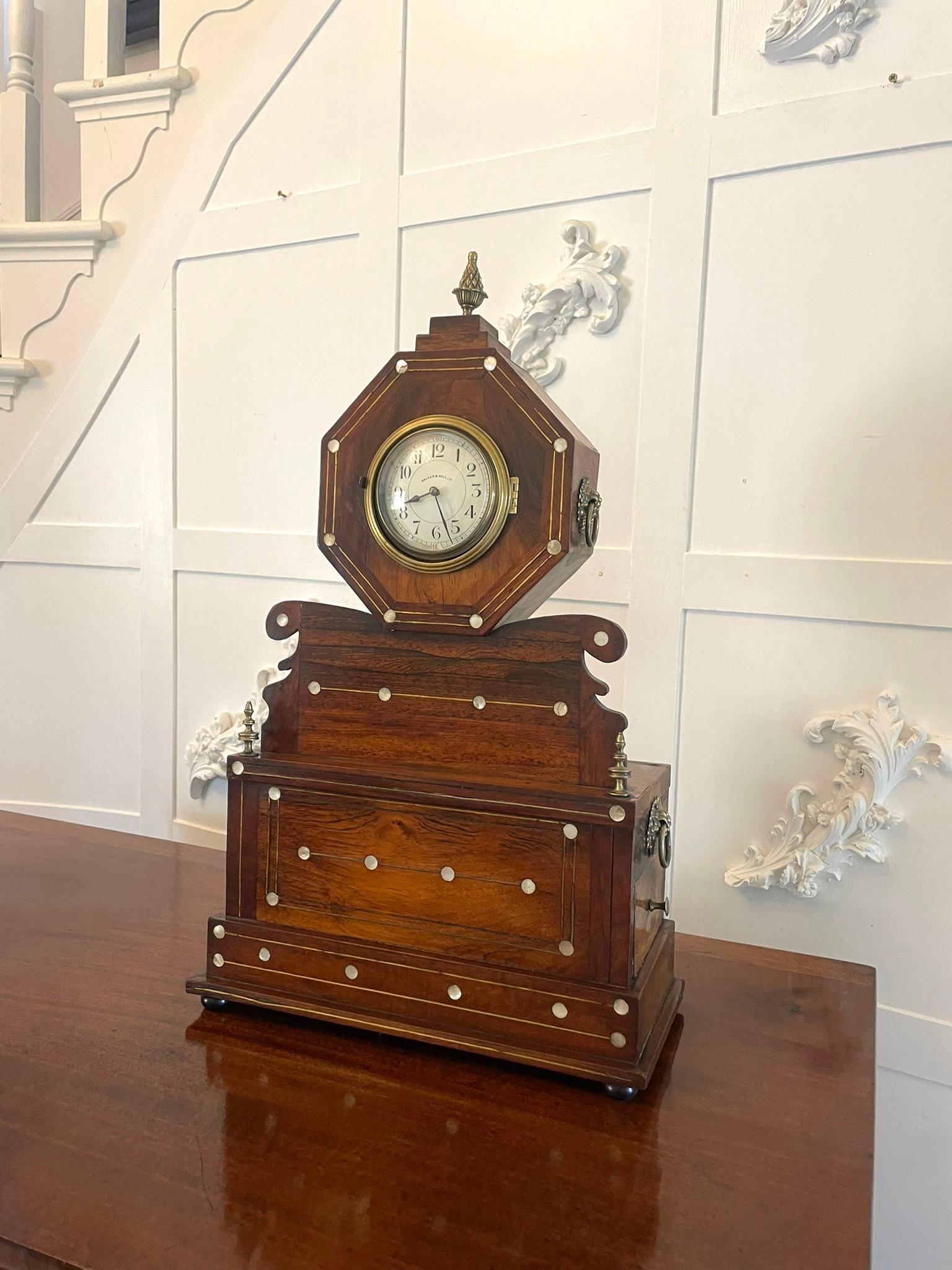 Antique rosewood inlaid mantle clock by Walker and Hall having a pretty and unusual rosewood Mother of Pearl and brass inlaid case with an eight day movement. It boasts a porcelain dial, original hands, original brass pineapple finial to the top,