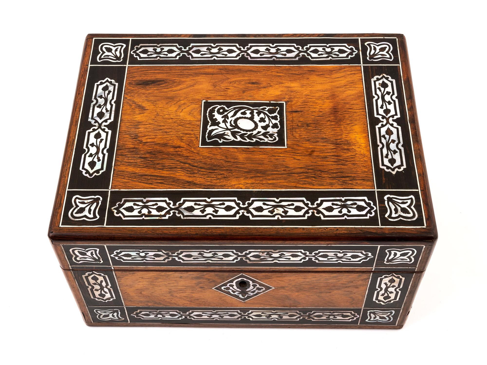 Behold the stunning Rosewood jewellery box, adorned with an exquisite symmetrical Mother of Pearl inlay that graces the top, front, key profile, and vacant initial plaque.

Its luxurious exterior will undoubtedly make a statement in any room,