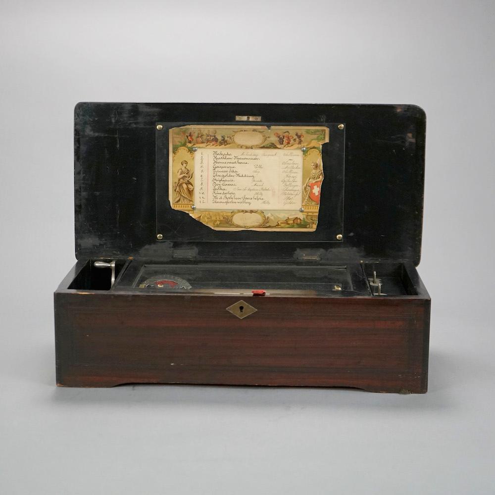 An antique Swiss music box offers rosewood case with tune card, banding and floral marquetry inlay, c1890

Measures- 5.5'' H x 18.75'' W x 9'' D.