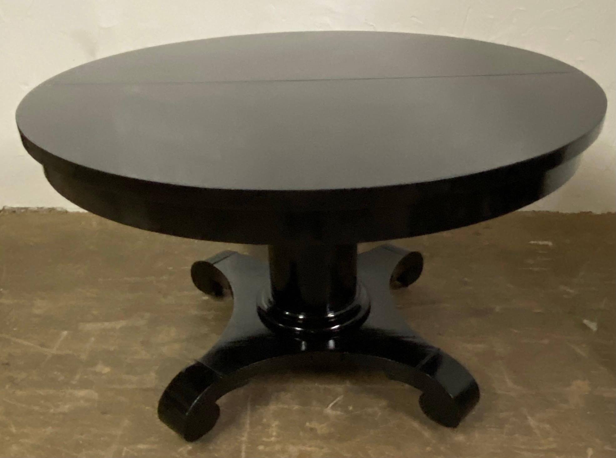 A handsome round black Regency style center pedestal dining table.
The round American Empire has four scrolled feet on wheels attached to a center pedestal. The table has been refinished in ebony black with a lacquered top. Although the table can