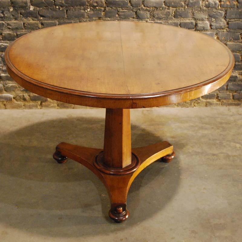 A beautiful English Regency center table with a solid mahogany top. The top is made of two slabs of Cuba Mahogany. The top has a short mahogany veneered apron. The table stands on a tripartite base with bun feet. An octagonal tapered column supports