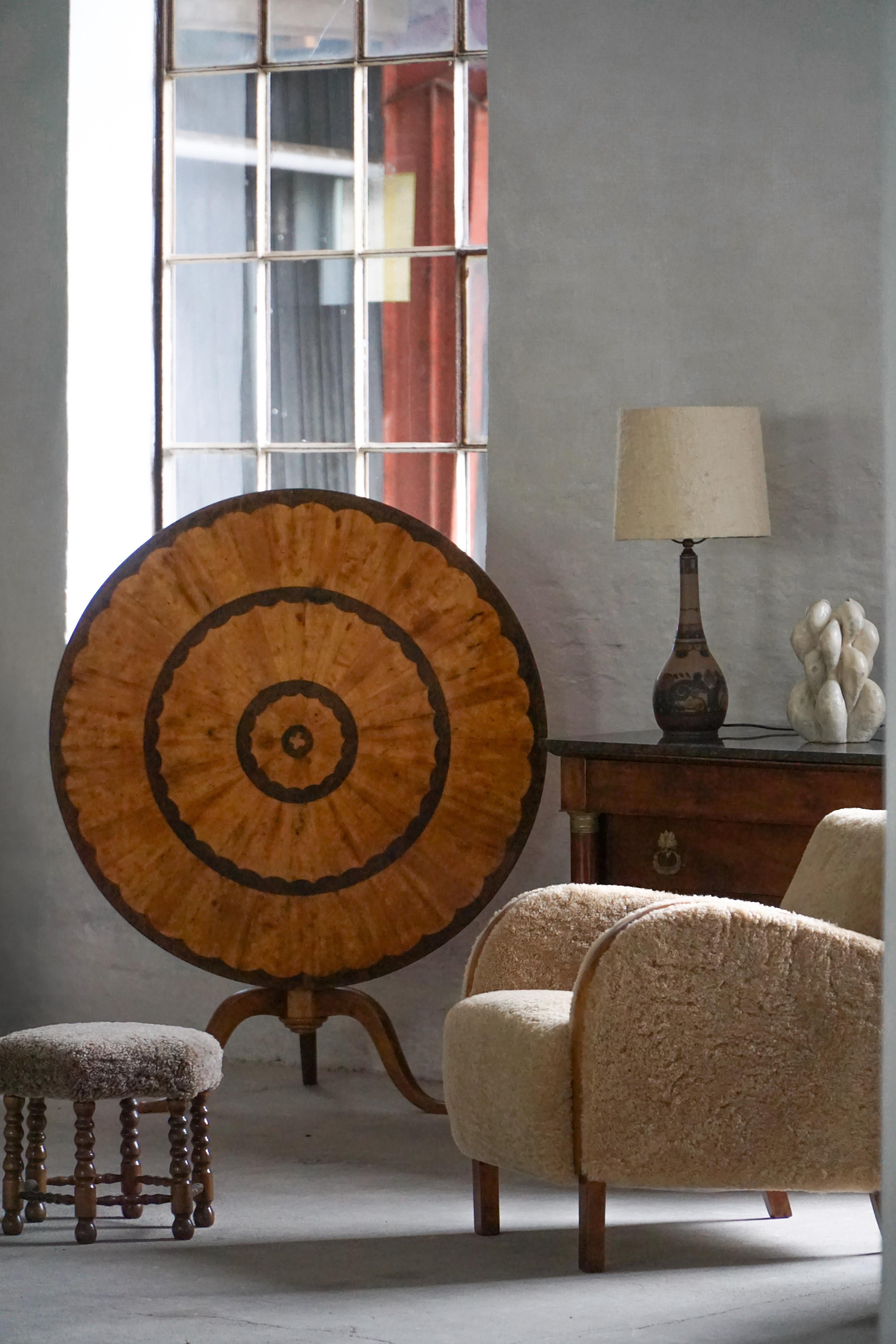 Un bellissimo tavolo rotondo svedese pieghevole in legno di radica/impiallacciatura di radice, risalente agli inizi del XIX secolo. Presenta un piano in legno laccato con un design grafico circolare e una base a piedistallo con gambe ricurve, che