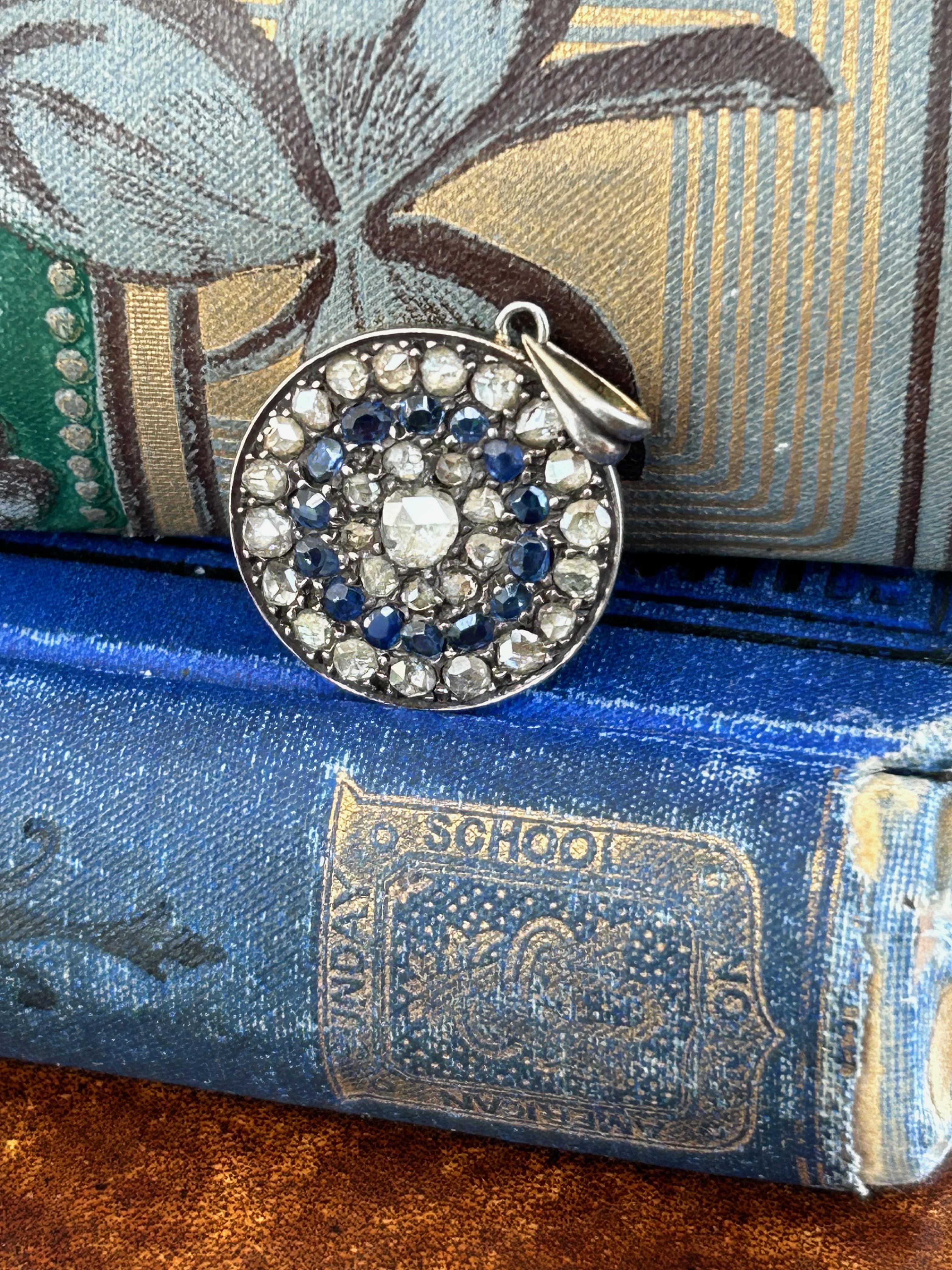 Description:
Antique Victorian Diamond and Sapphire Round Pendant, a stunning cluster design that seamlessly blends a lovely patina with old-world charm with timeless beauty.

Features:
Center Stone: A 4mm old Rose Cut Diamond, weighing .15 carats,