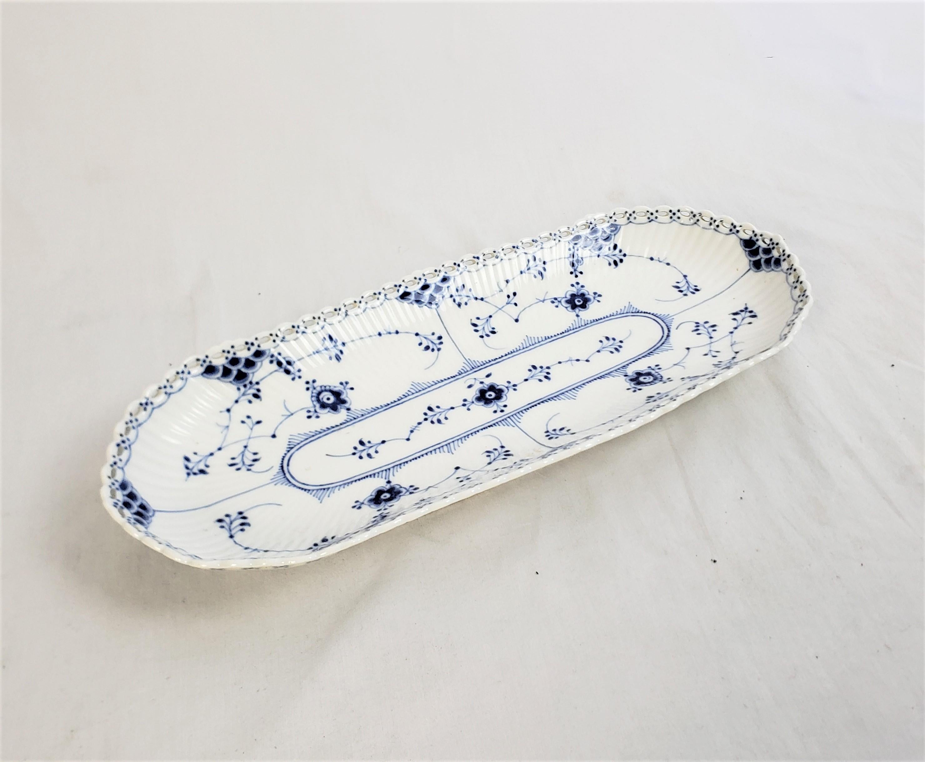 This antique serving dish was made by the well known Royal Copenhagen factory of Denmark in approximately 1920 in their signature style. The server is composed of porcelain and is done in their classic blue fluted full lace pattern. The piece is