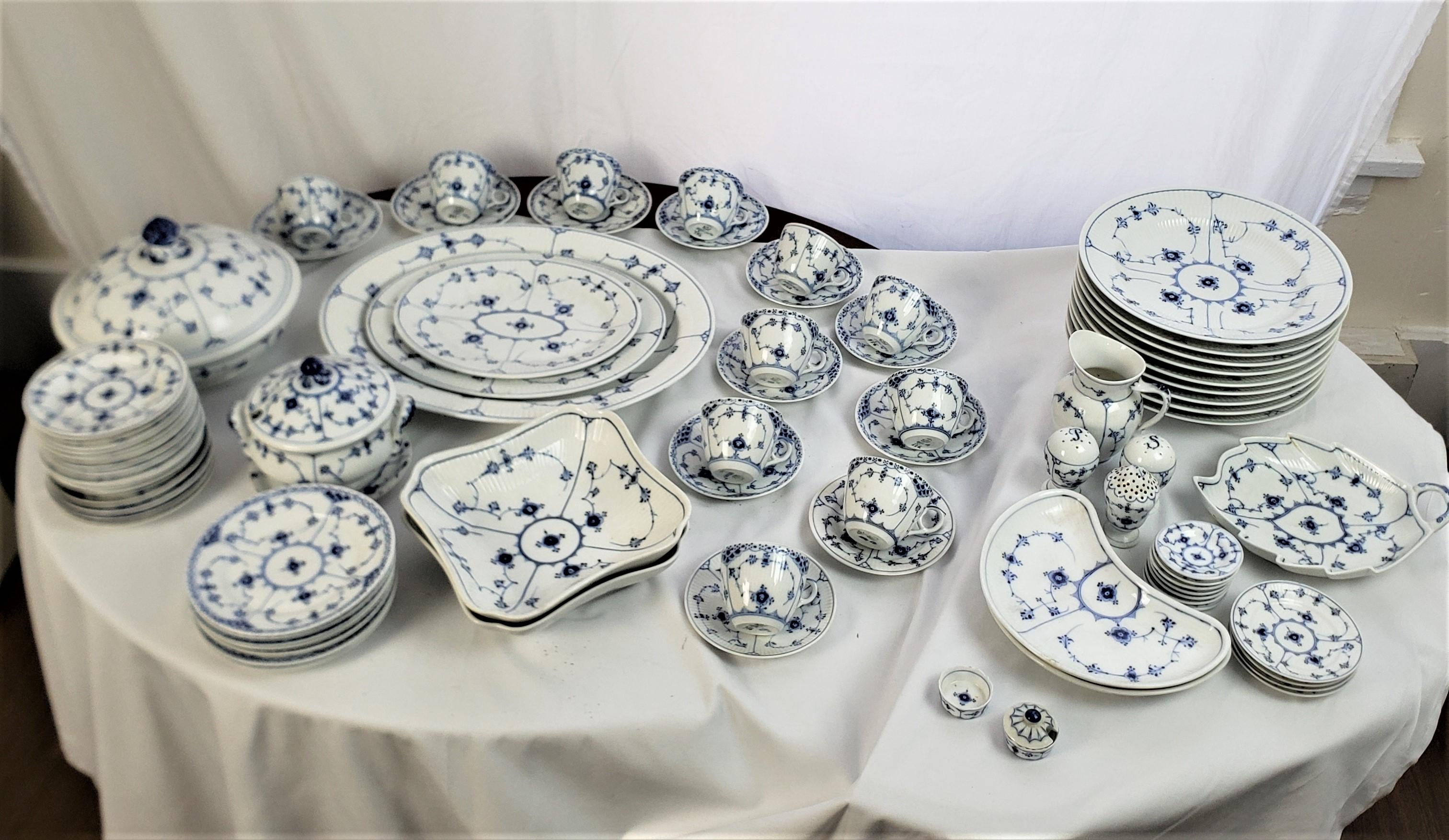 This antique partial mixed dinner service was made by the well known Royal Copenhagen factory of Denmark between 1880 and 1920, in their signature style. The set is composed of porcelain and is done in their classic blue fluted half lace pattern.