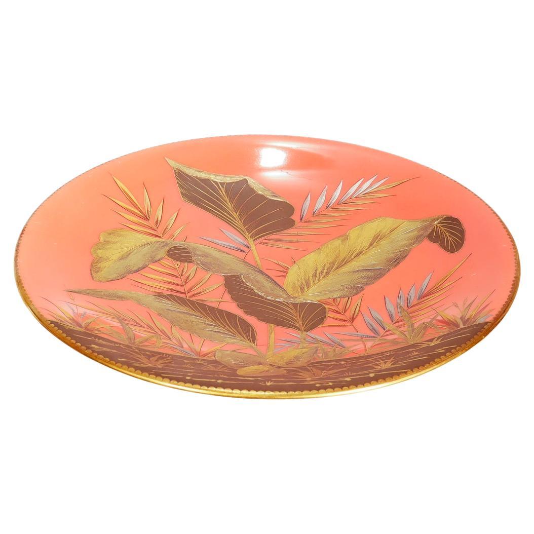 A fine Aesthetic Period porcelain plate.

By Royal Crown Derby.

Richly decorated with detailed leaves & plants in gold and platinum on a coral colored ground ground and a gilt rim.

Marked to the base with a Royal Crown Derby mark / No.
