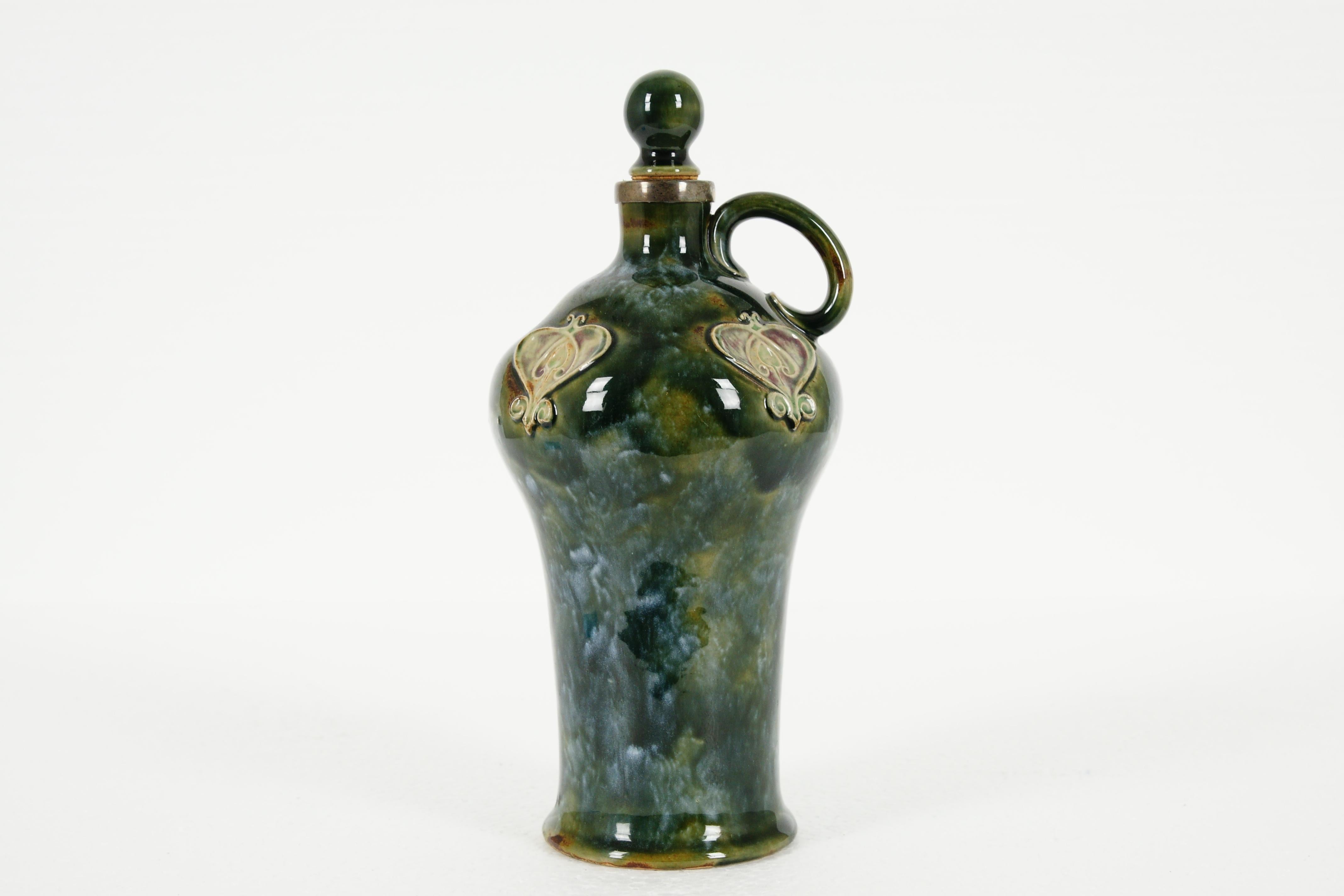 Antique Royal Doulton, Lambeth Stoneware, decanter/whisky bottle, with stopper. 9313, B1971

Inverse baluster shape with green glaze
Decorated with Art Nouveau design
Shaped handle to the side
Marked with Doulton Lambeth
Excellent