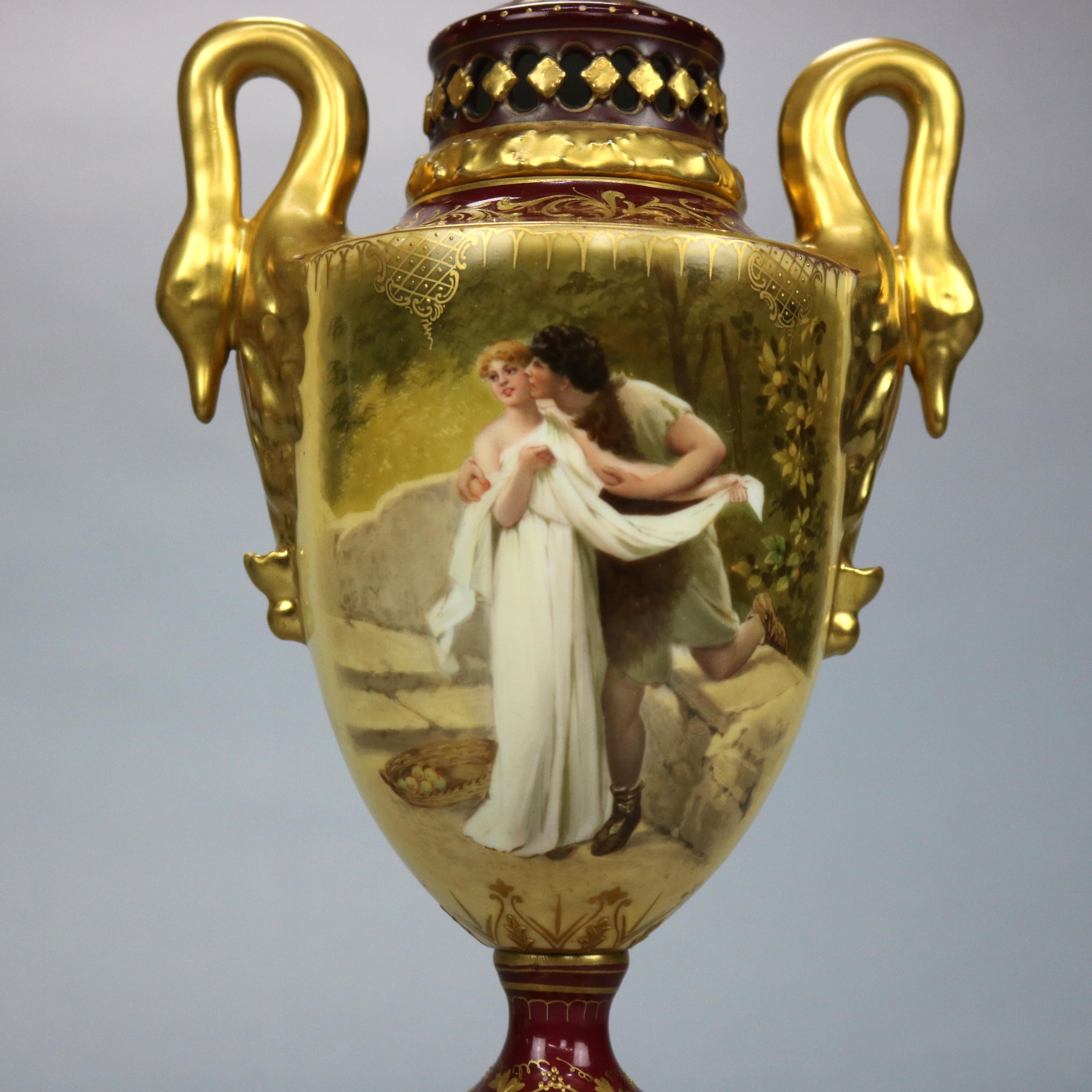 An antique Austrian portrait urn by Royal Vienna offers porcelain vessel in cobalt blue glaze with pierced upper having gilt wreath over bowl with hand painted courting scene flanked by double figural gooseneck handles, raised on decorated square
