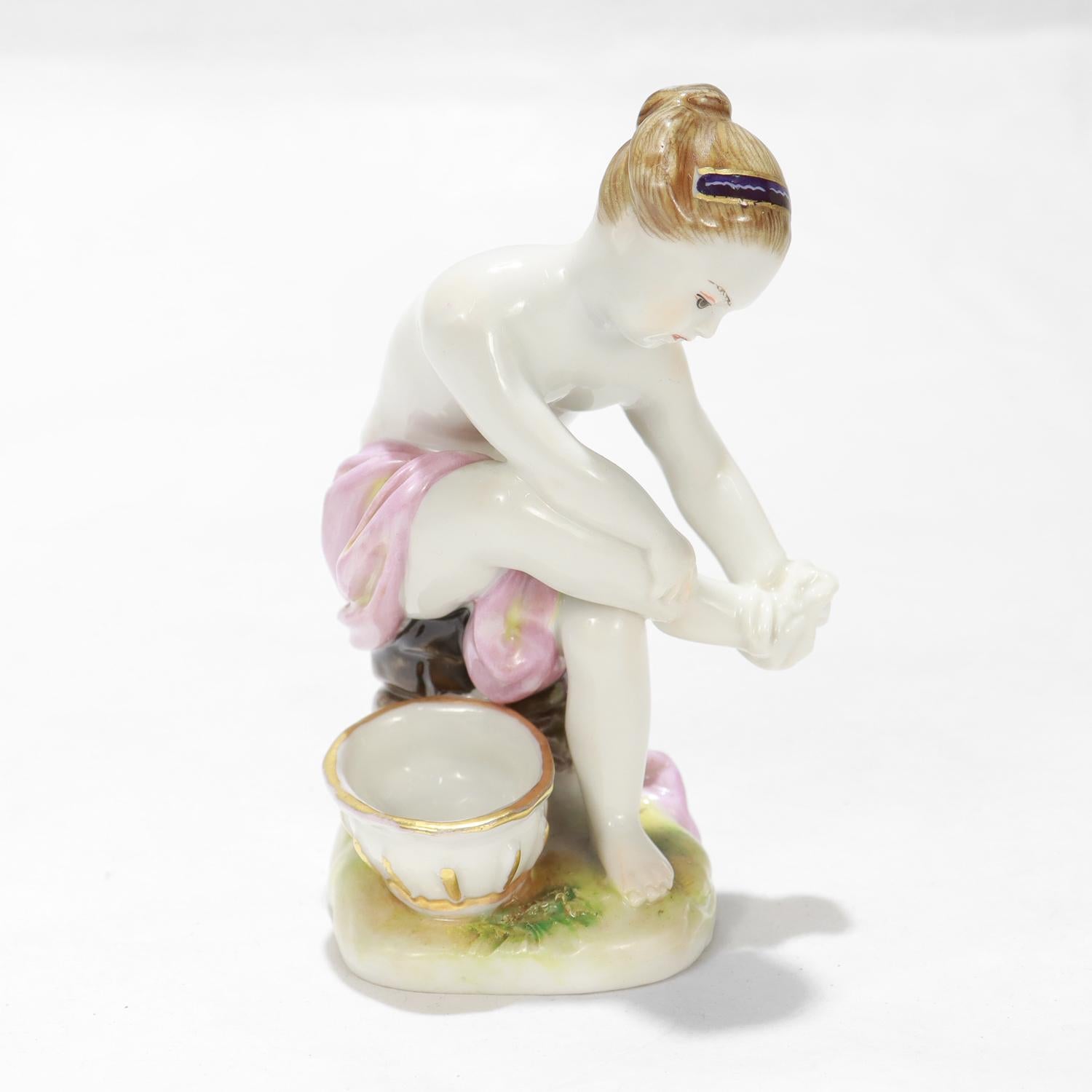 A fine antique porcelain figurine.

By the Royal Vienna Porcelain Manufactory.

In the form of a seated girl bathing her feet with a water bowl resting next to her atop a plinth.

Marked to reverse of the plinth with a Royal Vienna blue underglaze