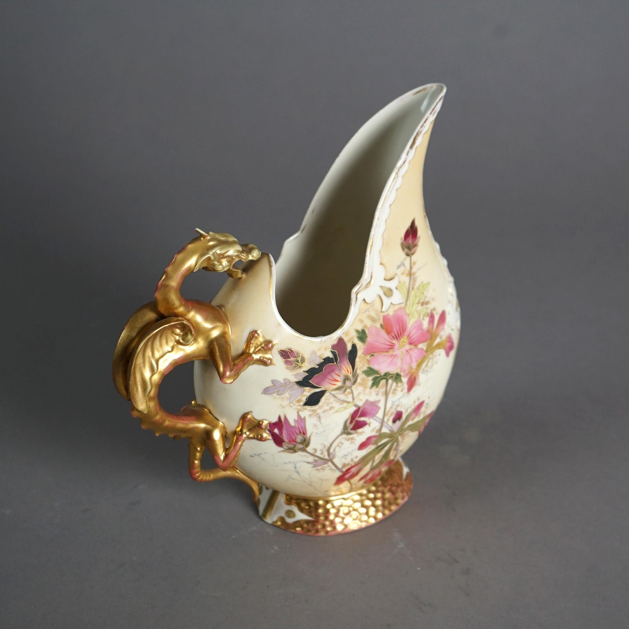 An antique ewer by Royal Worcester offers porcelain construction with hand painted and gilt floral decoration, figural dragon form handle and raised on circular gilt foot, 19th century

Measures- 9.5''H x 3.5''W x 8.5''D