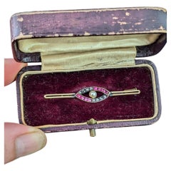 Broche antiguo con forma de ojo, de rubíes y diamantes, en su estuche, de oro de 9k