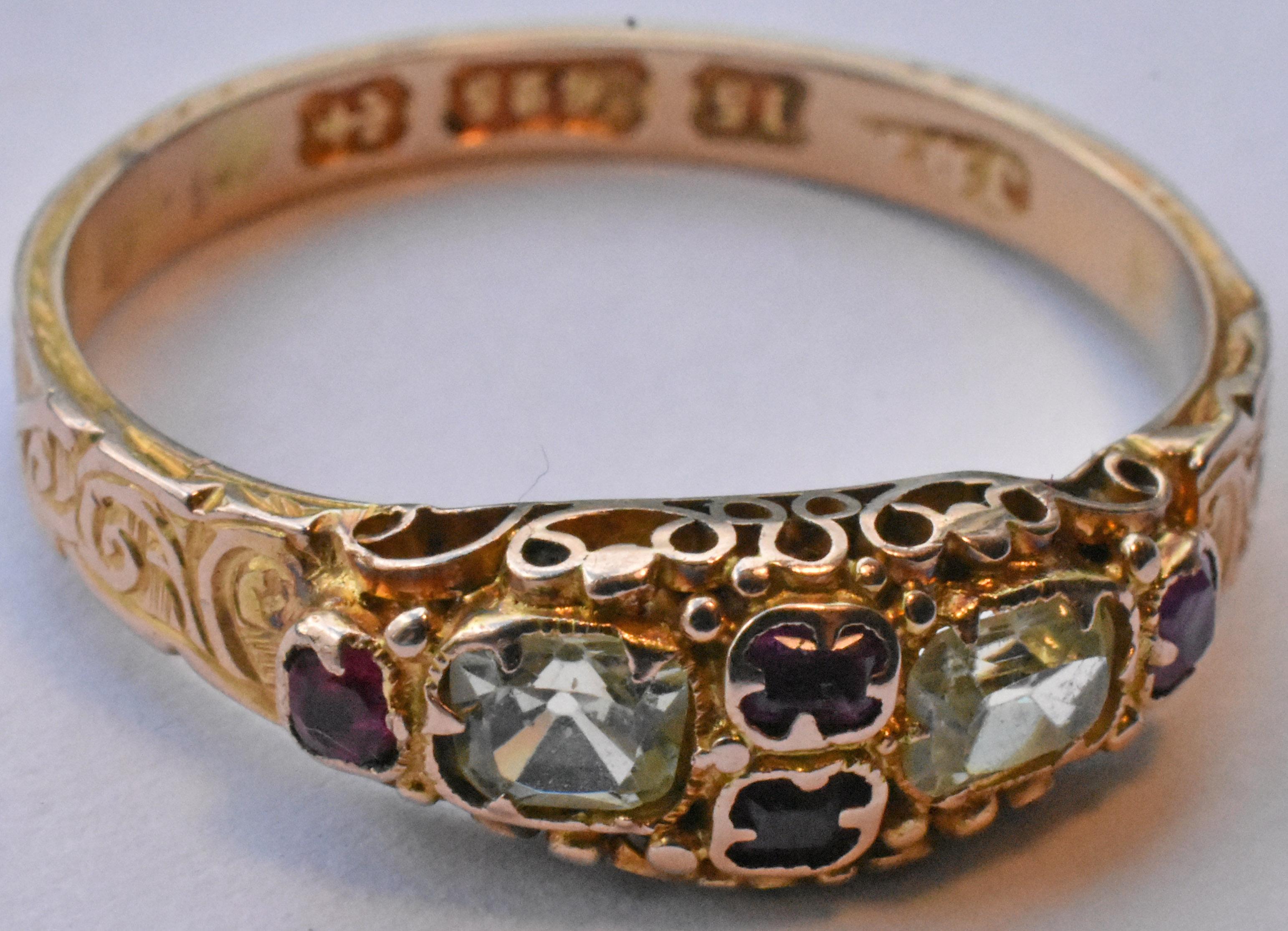 Lovely 15k early Victorian ring with two cushion cut chrysoberyls and four rubies, hallmarked Birmingham and dated 1868. Swirls, whorls and curlicues engraved along the band add interest and texture. Rubies are enclosed in a cloverleaf shaped