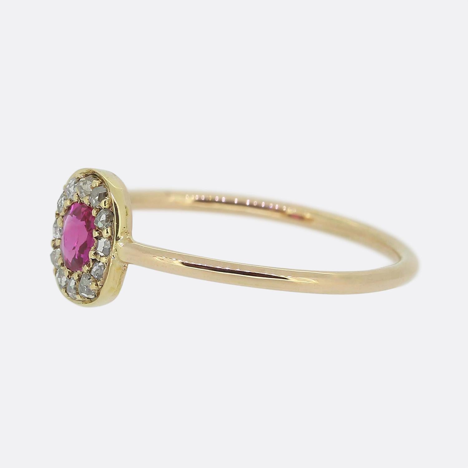 Here we have a charming ruby and diamond cluster ring. This piece has been crafted from a warm 18ct rose gold and showcases a single round faceted Burmese ruby possessing a vivid red colour with pinky undertone. This principal stone is then