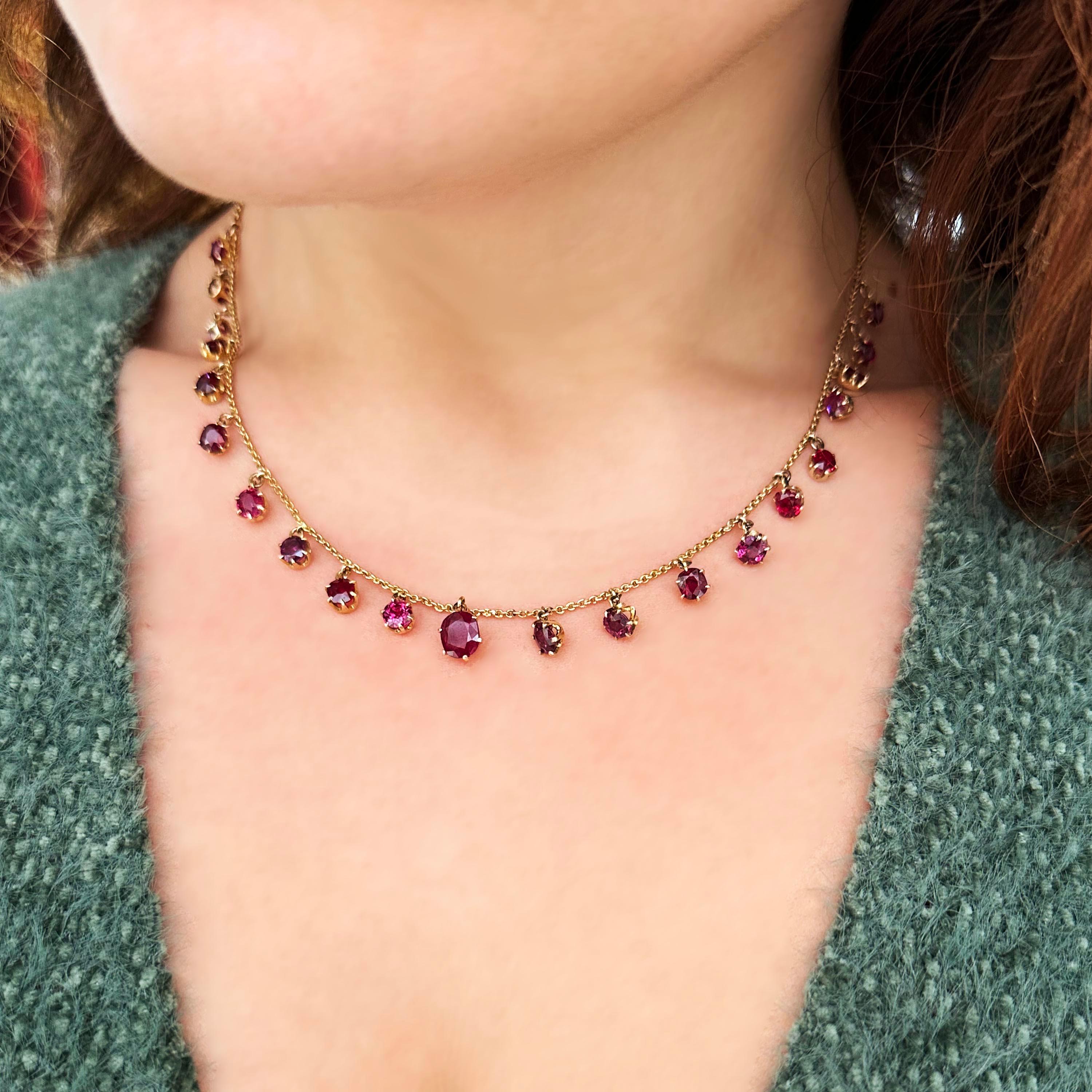 An antique ruby and gold necklace, with twenty-one cushion-cut ruby set pendants, graduating from the centre, in crown settings, onto a gold trace chain, with a jump and bolt ring clasp, circa 1920.