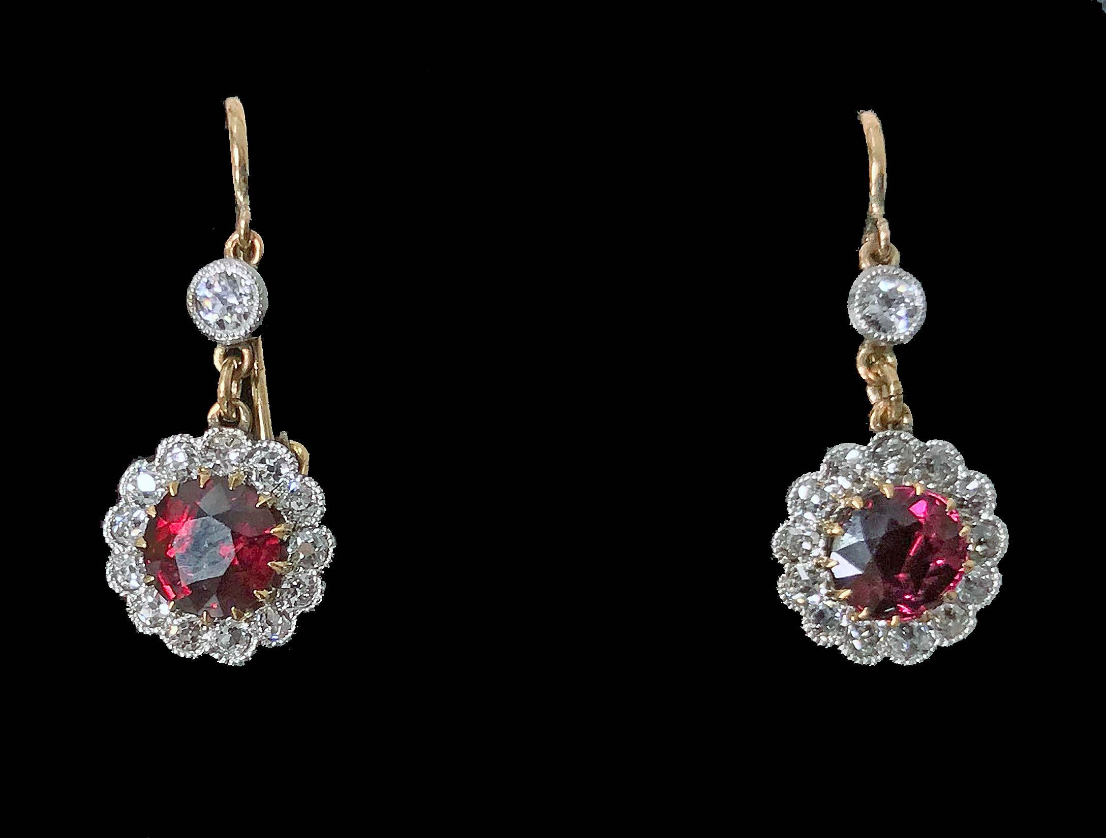 Pair of Antique Ruby and Diamond Gold and Platinum Earrings, C.1920. Each suspending a round facetted purplish Red Ruby, approximately 0.75 ct each, average VS2-SI1 clarity (type 11) with a milligrain set surround of 13 old mine cut diamonds