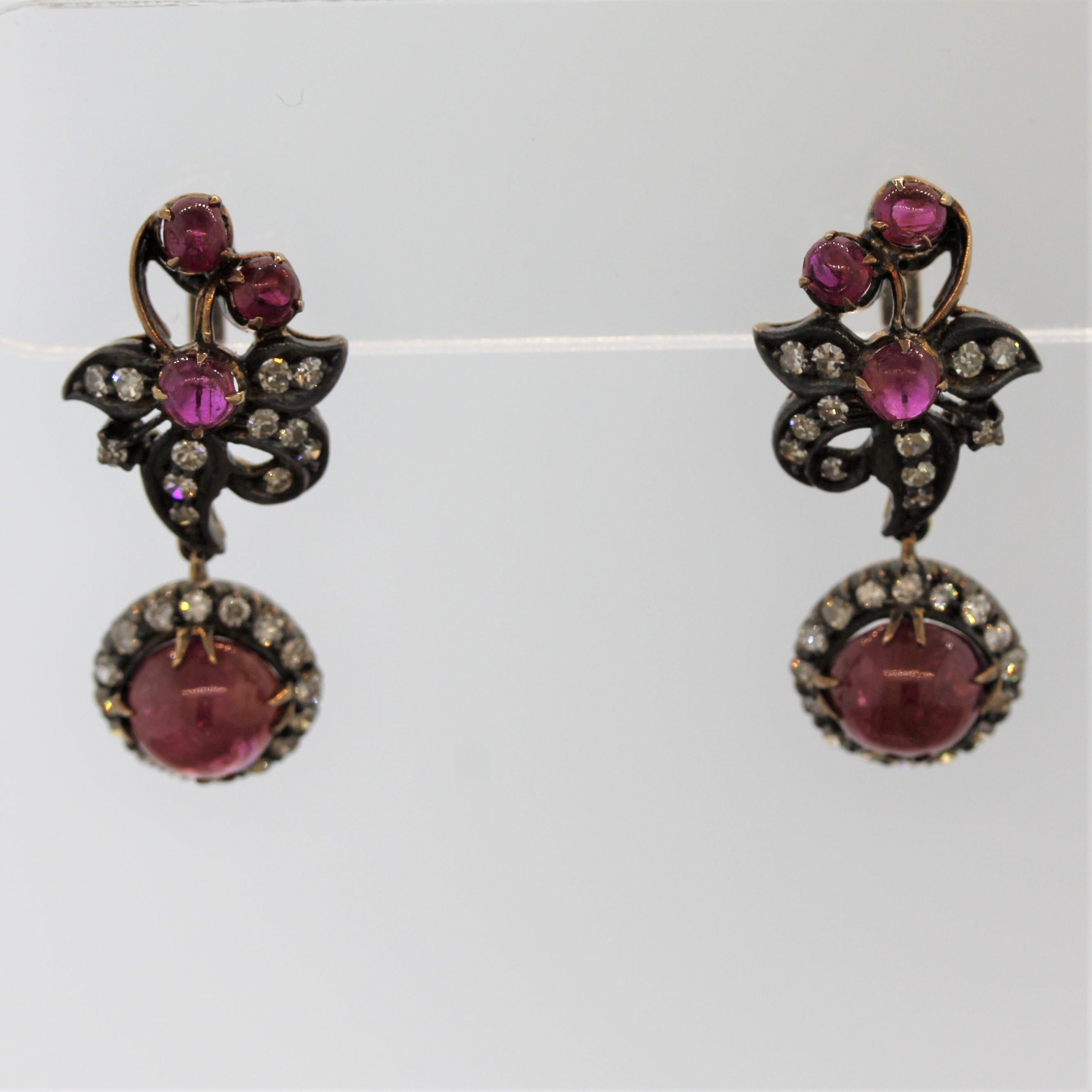 A sweet pair of antique earrings featuring bright red cabochon rubies. They are accented by round single cut diamonds set in 14k gold that has been silver-topped and turned a dark color which can only be achieved over many years.

Length: 1 inch