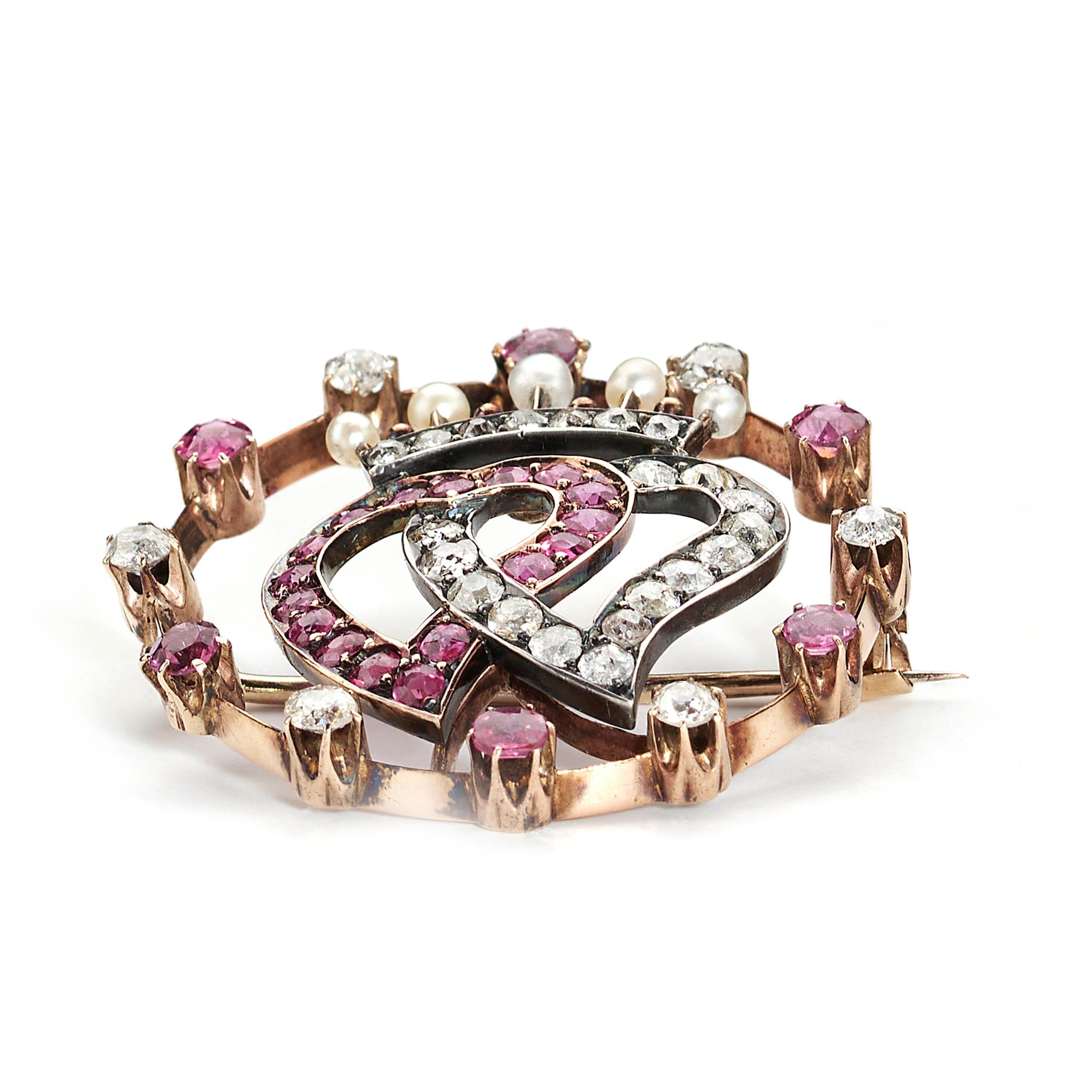 An early 20th century, Luckenbooth double witch's heart brooch, with one heart set with Burma rubies and the other set with old-cut diamonds, in grain settings, surmounted with a coronet, set with three, natural seed pearls, above a row of old-cut