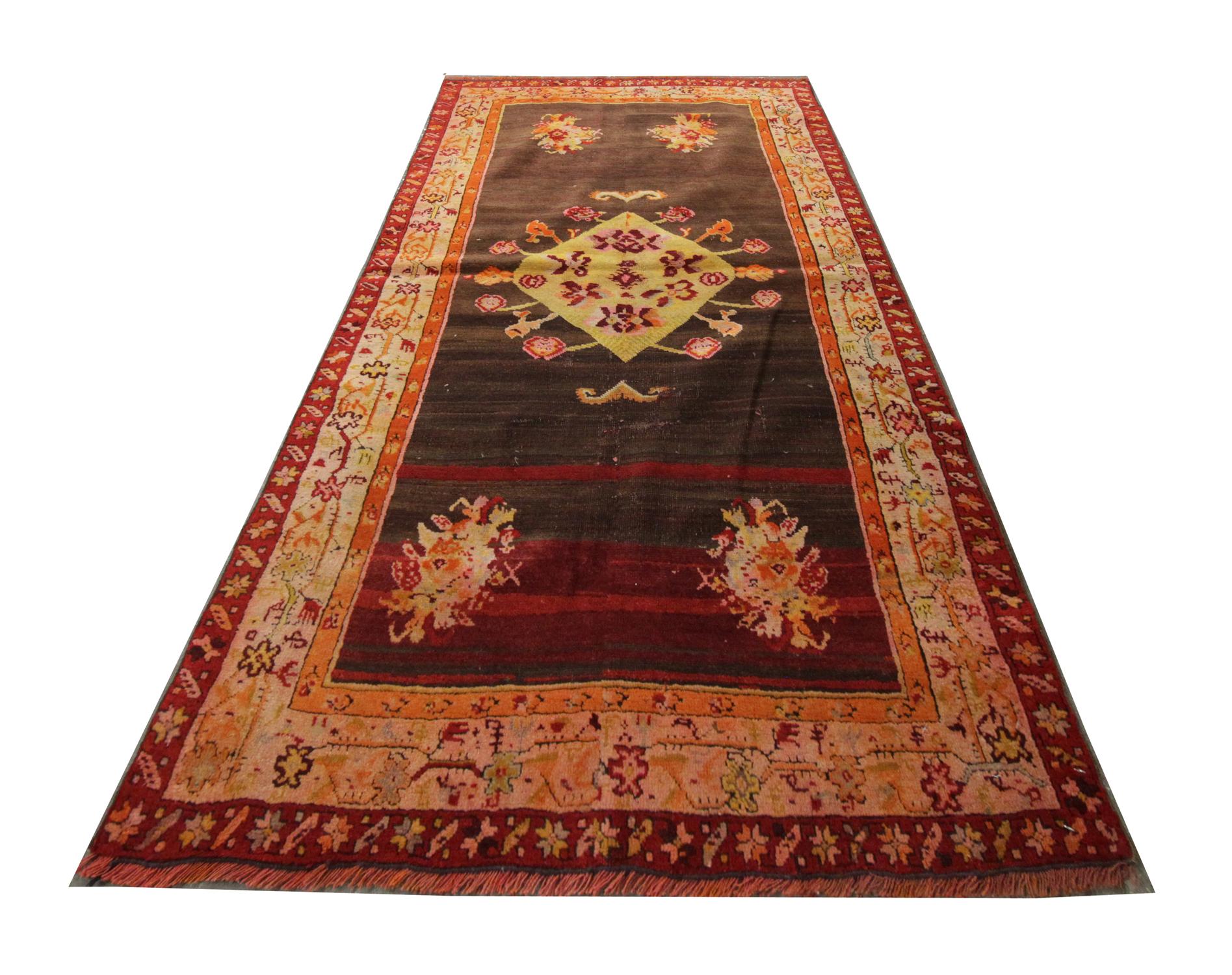 This Oriental rug handmade carpet features muted tones of brown and orange weaved with a rich floral multi-layered border and an intricate central motif. On a brown background, the central motif contrasts elegantly woven in yellow and orange. This