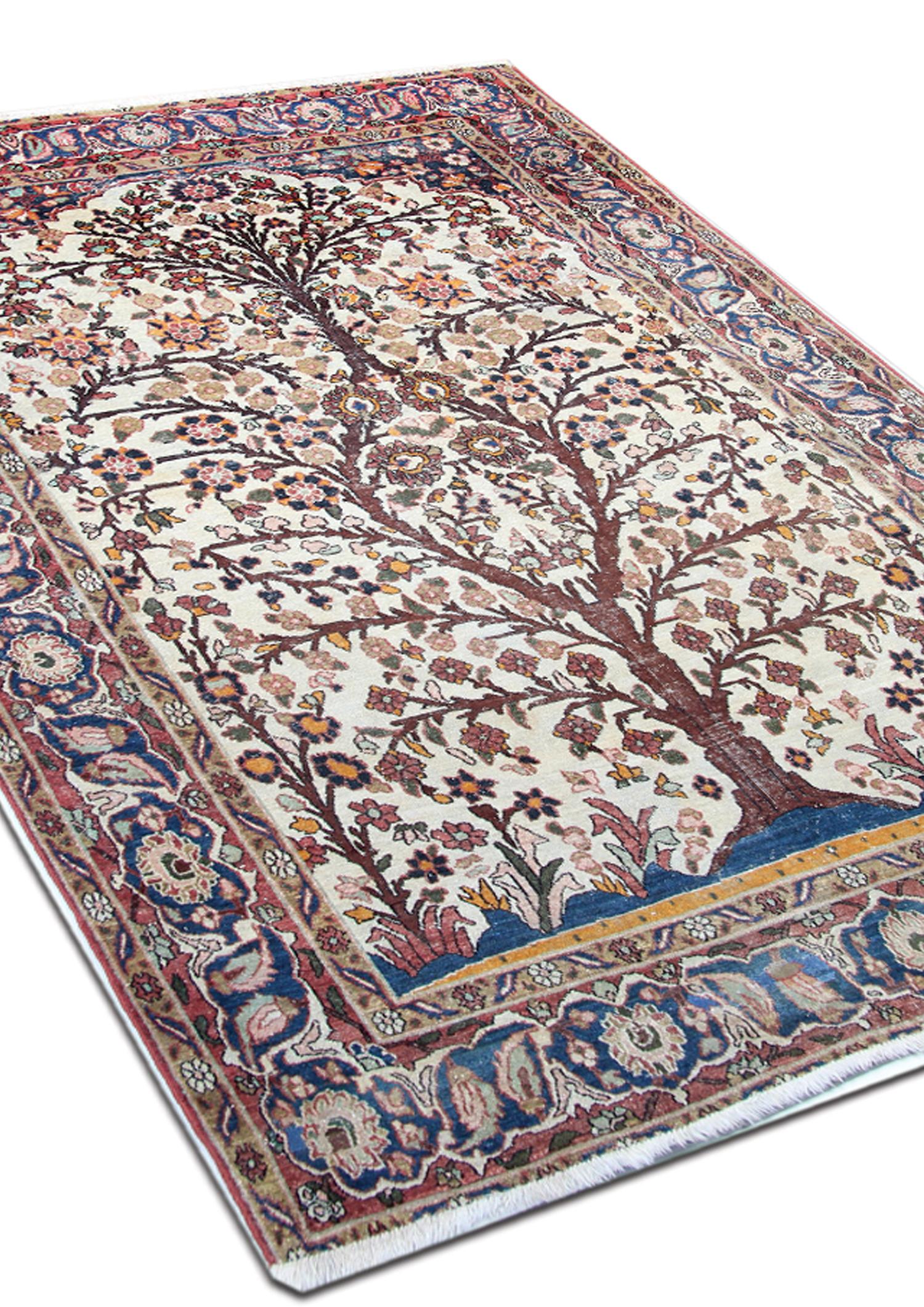An extraordinary early 20th-century Ivory rug with an incredible densely woven multi-coloured tree-of-life design with two sinuous trees on each side of the central field, each with myriad varieties of multicoloured flowers and leaves. The border is