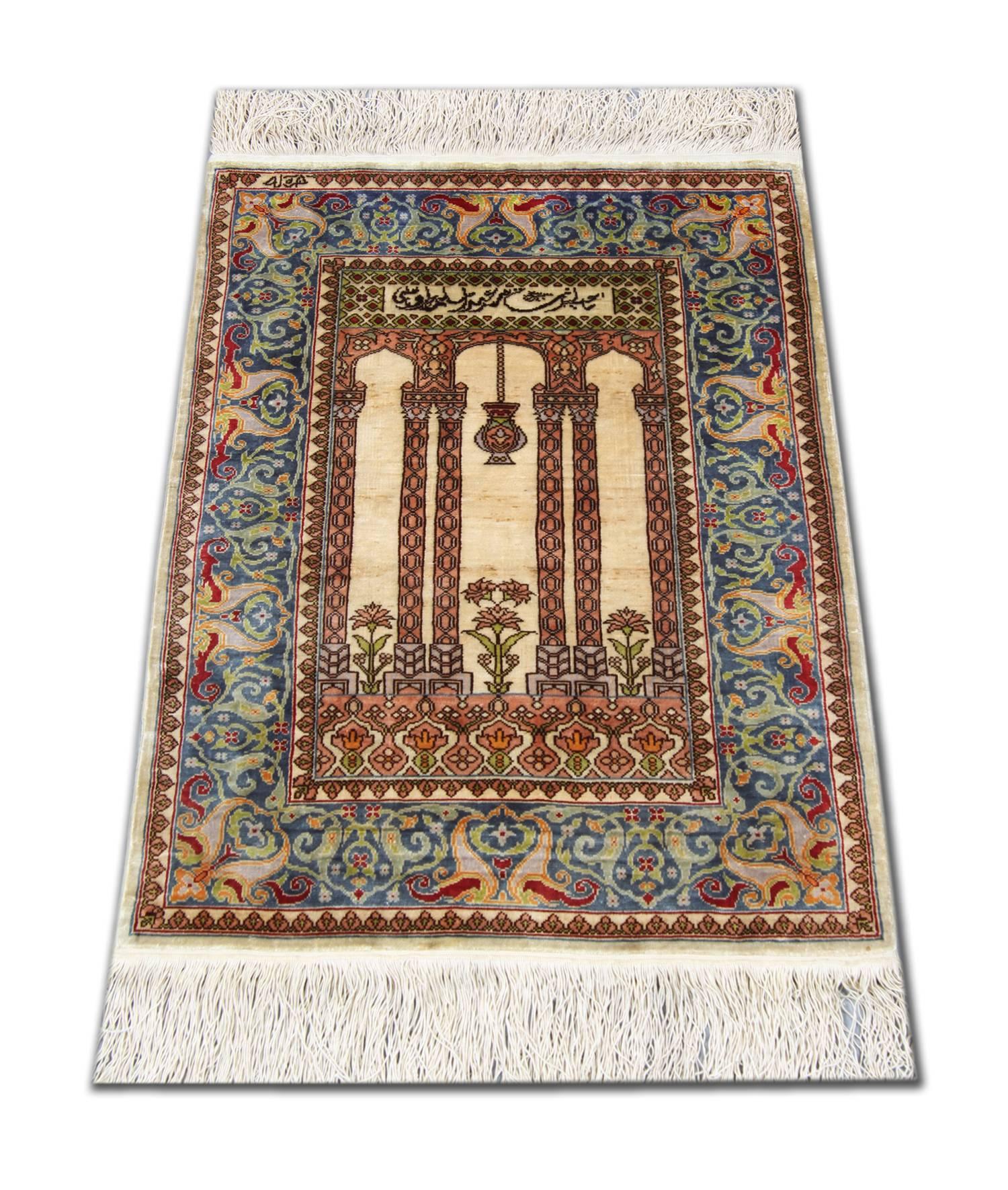 An antique Turkish silk Hereke woven rug, circa 1970. These fine handmade rugs feature a lustrous short silk pile with a tree of life design at one end of the ivory centre field, beautiful flower heads at the centre and an arch at the other end. The