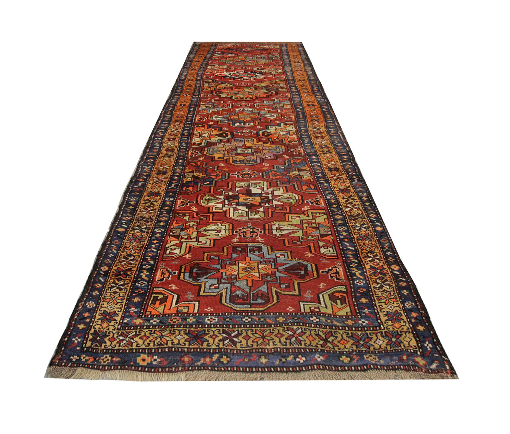 A handmade carpet with a repeat pattern of geometric designs flows through the centre of this Oriental rug, with colors of green blue and brown softly contrasting against the deep orange background, enclosed with a repeat motif border. Rich in