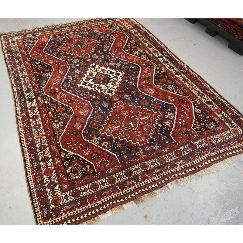 Antiker Teppich mit Stammesmuster aus der Region Shiraz, wahrscheinlich von sesshaften Knüpfern des Khamseh- oder Qashqai-Stammes.

Ein guter Teppich mit dreifachen Medaillons, der viele Stammesmusterelemente enthält. Der Teppich hat eine
